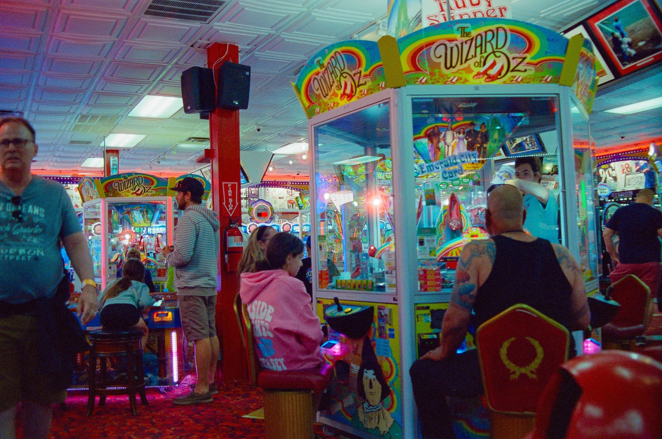 Arcade inside a casino with people playing and colorful game machines, including a 'Wizard of Oz' themed game.