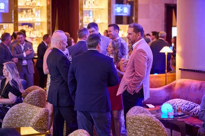 Group of people socializing at a lounge or bar with warm lighting and modern decor