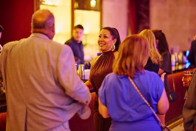 People socializing at a bar or nightclub with colorful lighting