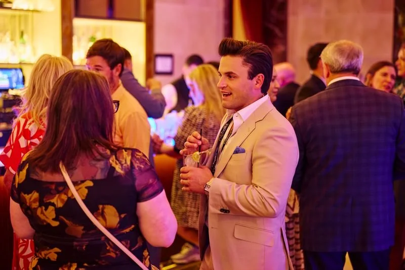 People socializing and networking at a party or reception in an indoor venue with warm lighting.