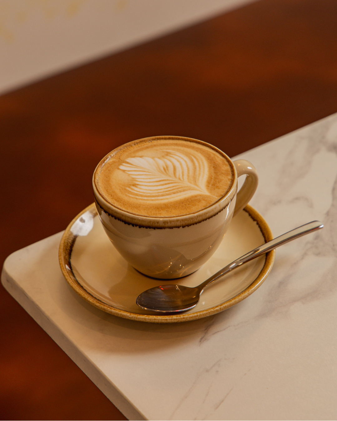 Best coffee McMahons Point - Allpress Espresso flat white with perfect rosetta latte art on marble table at Bene & Co Blues Point Road cafe
