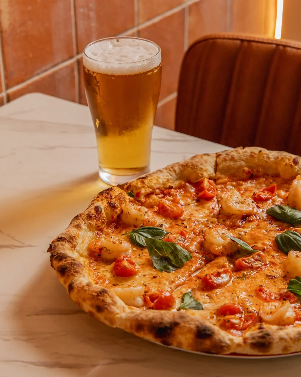 A $25 lunch special in North Sydney featuring a traditional wood-fired pizza with fresh basil and cherry tomatoes paired with a cold beer at Bene & Co.