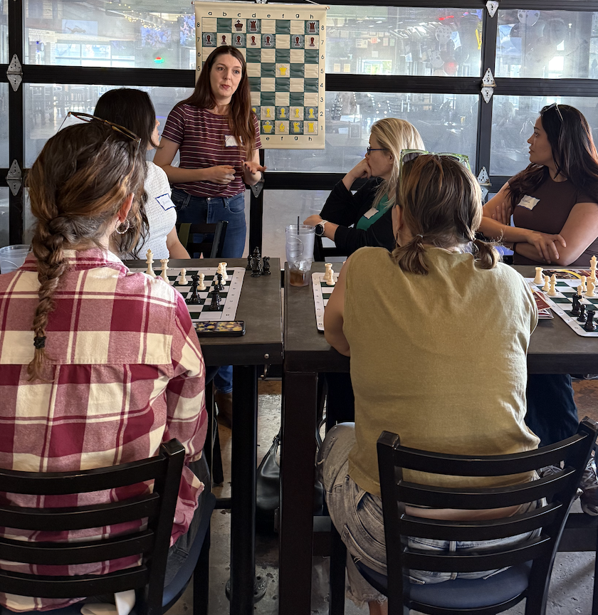 A young man deeply focused on a chess game in a bar, with glasses of beer on the table and other patrons in the background.