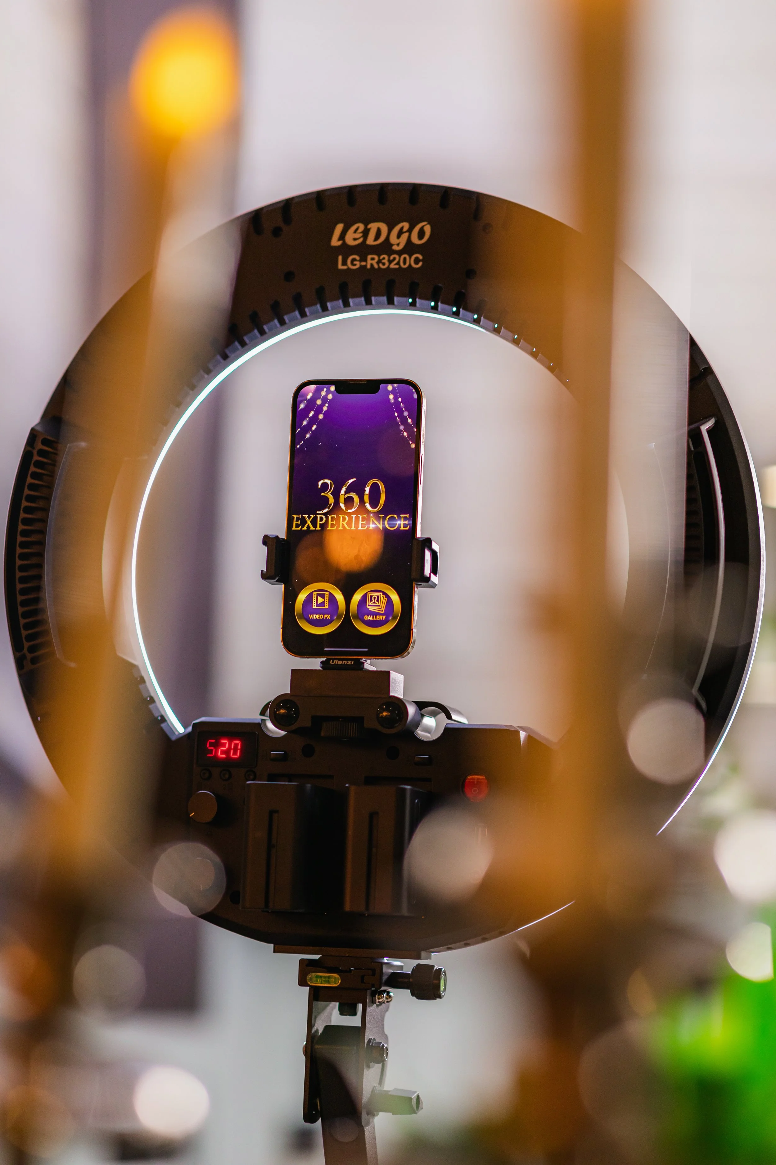 A smartphone mounted on a tripod inside a ring light, displaying a screen with the words '360 EXPERIENCE' and two icons labeled 'Video FX' and 'Gallery'.