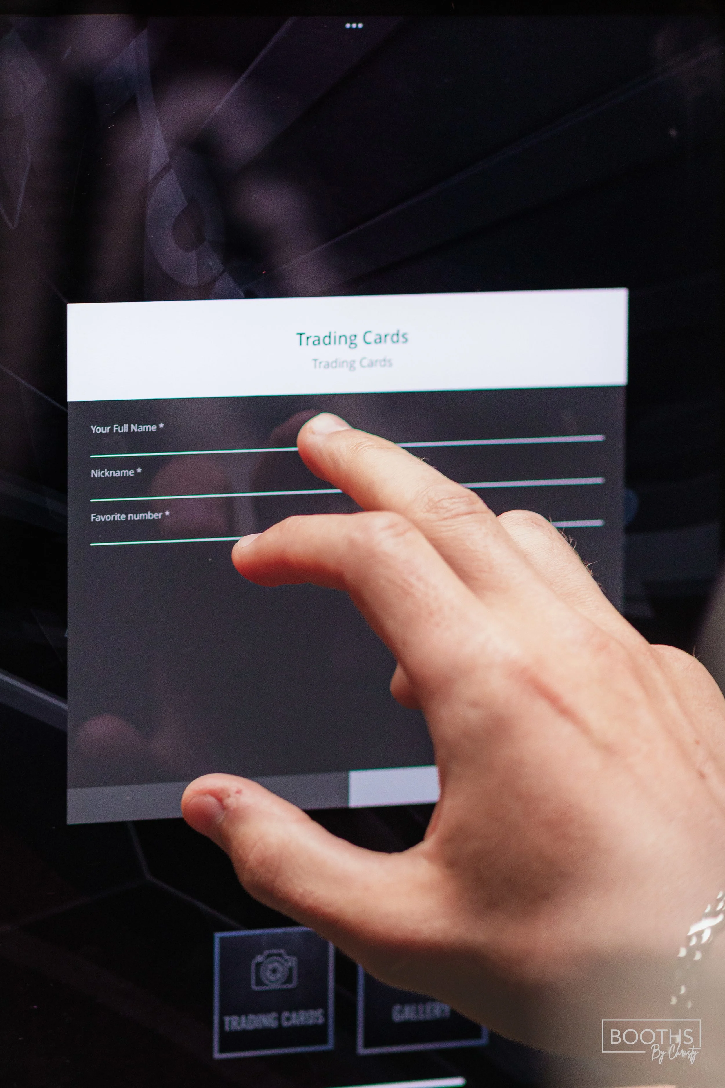 Person using a touchscreen device to fill out a digital form for trading cards on a tablet screen, with options for full name, nickname, and favorite number.
