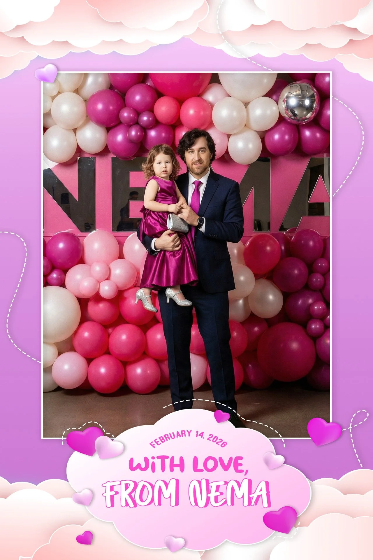 A man in a dark suit holding a young girl in a pink dress at a celebration with pink and white balloons and a pink backdrop with the word "NEMA" behind them. The image has a decorative pink cloud border with purple hearts and a message saying "Februa