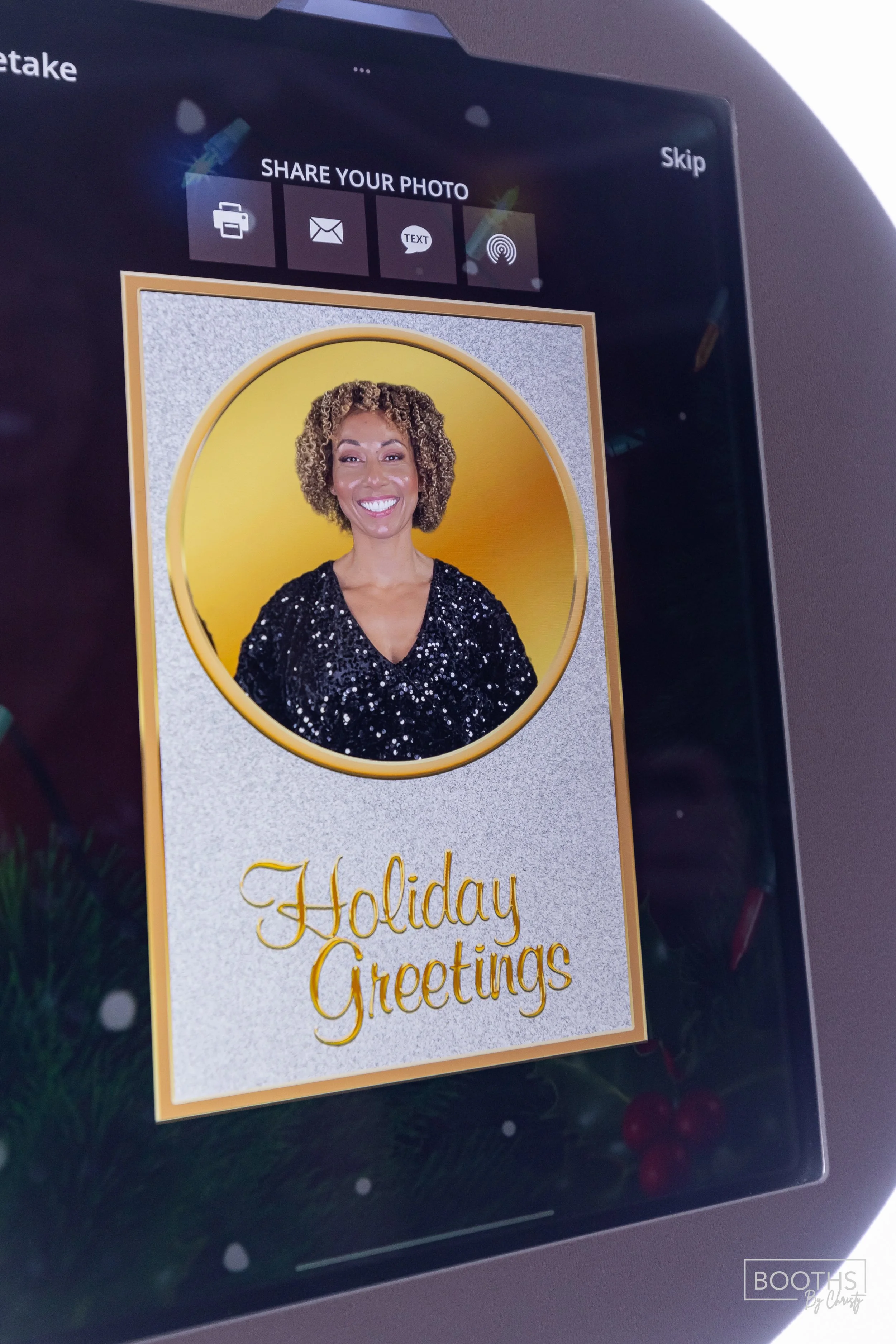 A digital photo booth screen displays a smiling woman in front of a yellow background with a holiday greeting that says, 'Holiday Greetings', and options to share the photo via printer, email, text, or wireless download.