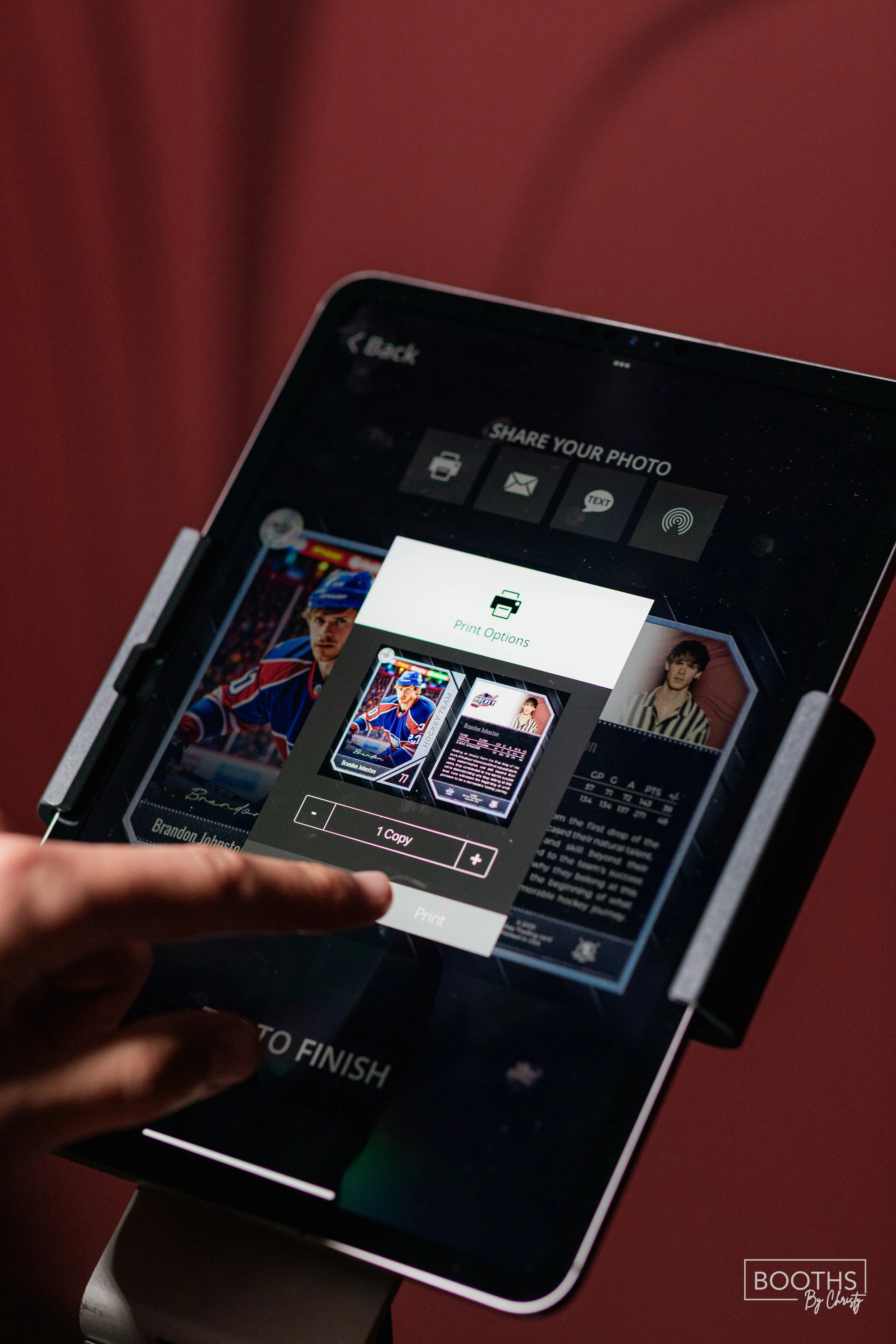 Close-up of a person's hand selecting print options for a photo on a tablet, which displays a hockey player and a sports card.