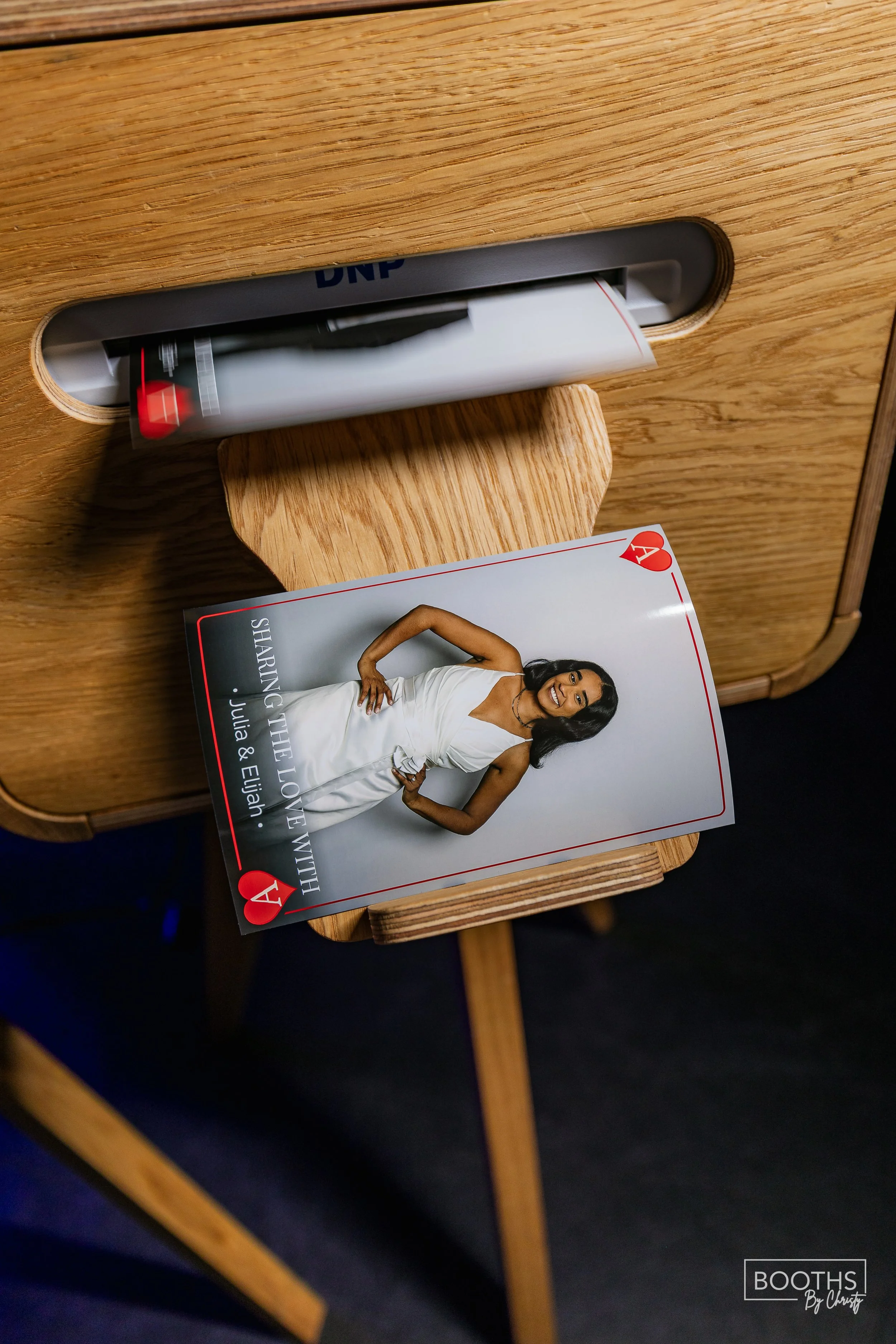 A brochure with a woman in a white dress holding a wine glass, on a wooden table next to a red and white promotional display or stand.