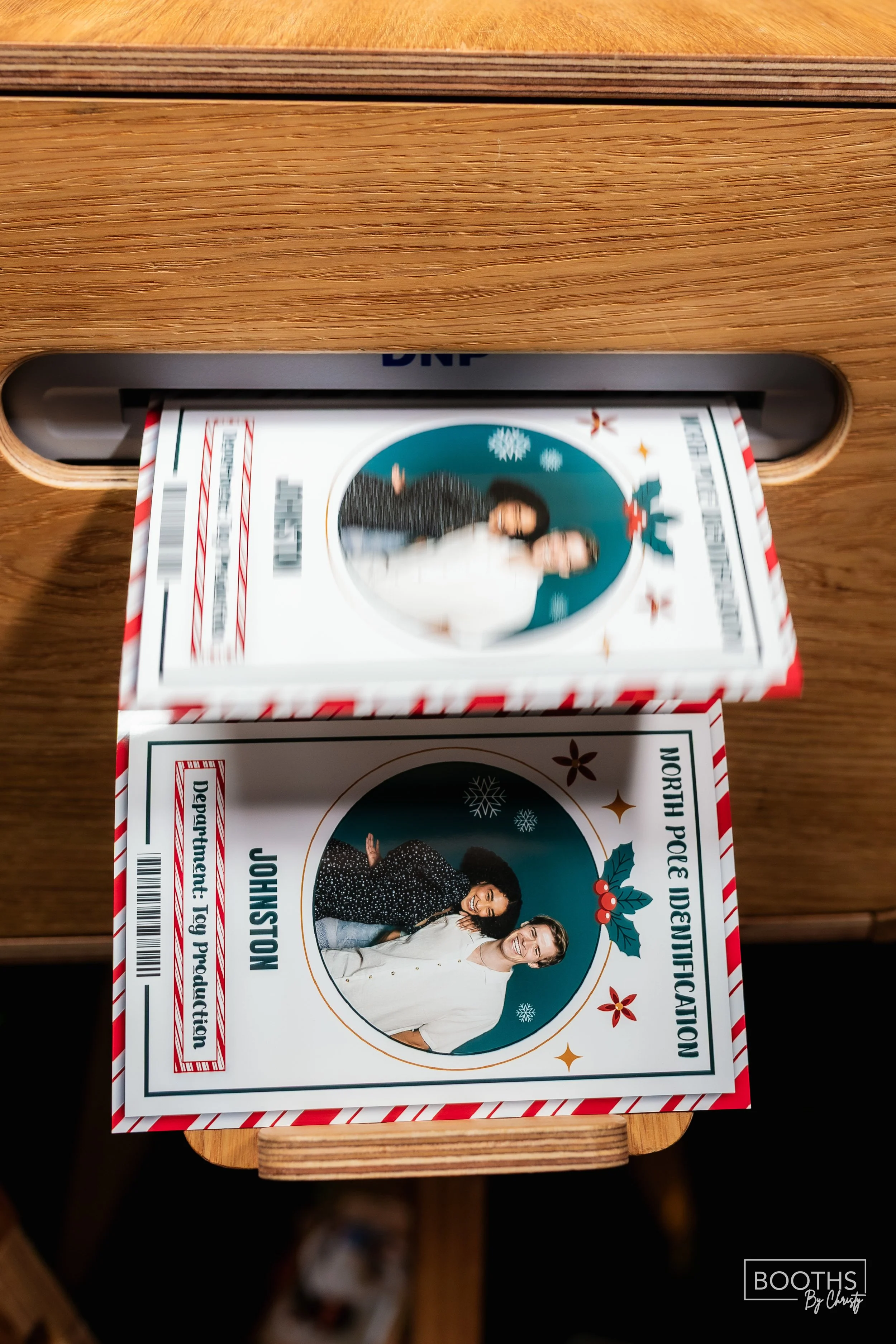 A North Pole Identification pamphlet featuring a photo of two women smiling, decorated with Christmas themed illustrations like holly and snowflakes.