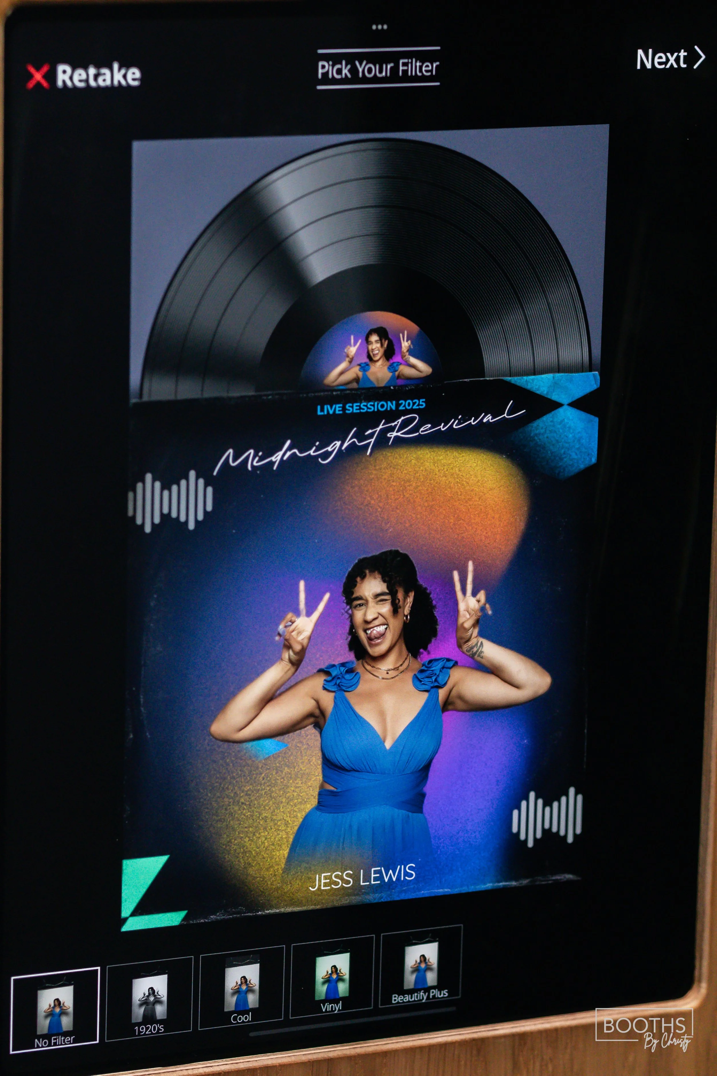 Digital photo booth display showing a woman in a blue dress making peace signs and sticking her tongue out. The display promotes a live music event titled Midnight Revival with Jess Lewis, featuring colorful graphics and sound wave icons.