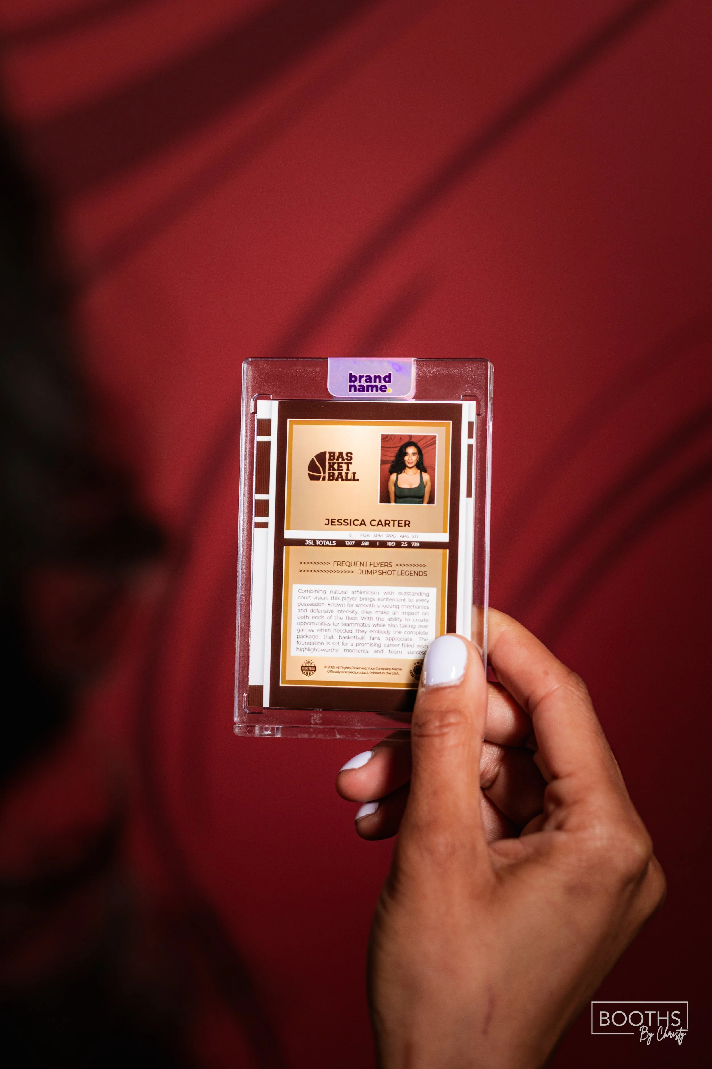 Close-up of a basketball player profile card for Jessica Carter, held in someone's hand with a red wooden floor background.