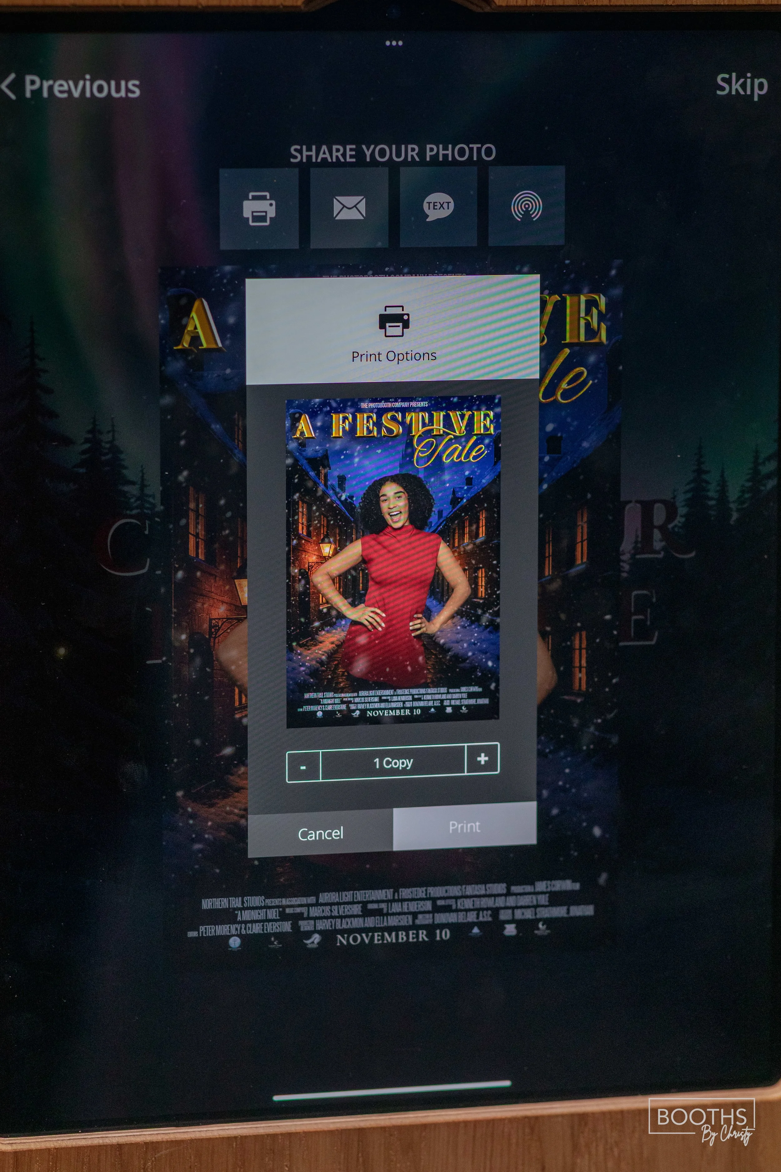 A digital screen displaying a poster for a festive holiday event date November 10, featuring a woman in a red dress standing in a snowy street scene with lit windows and outdoor street lamps.