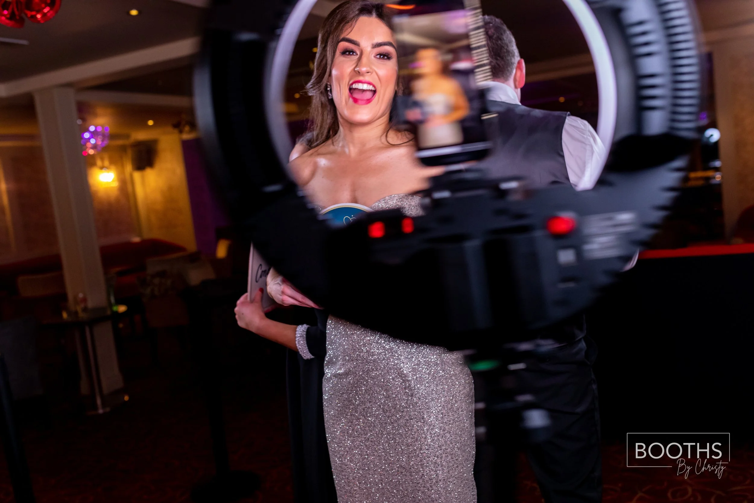A woman in a sparkly dress posing for a photo at an event, seen through a camera's viewfinder.