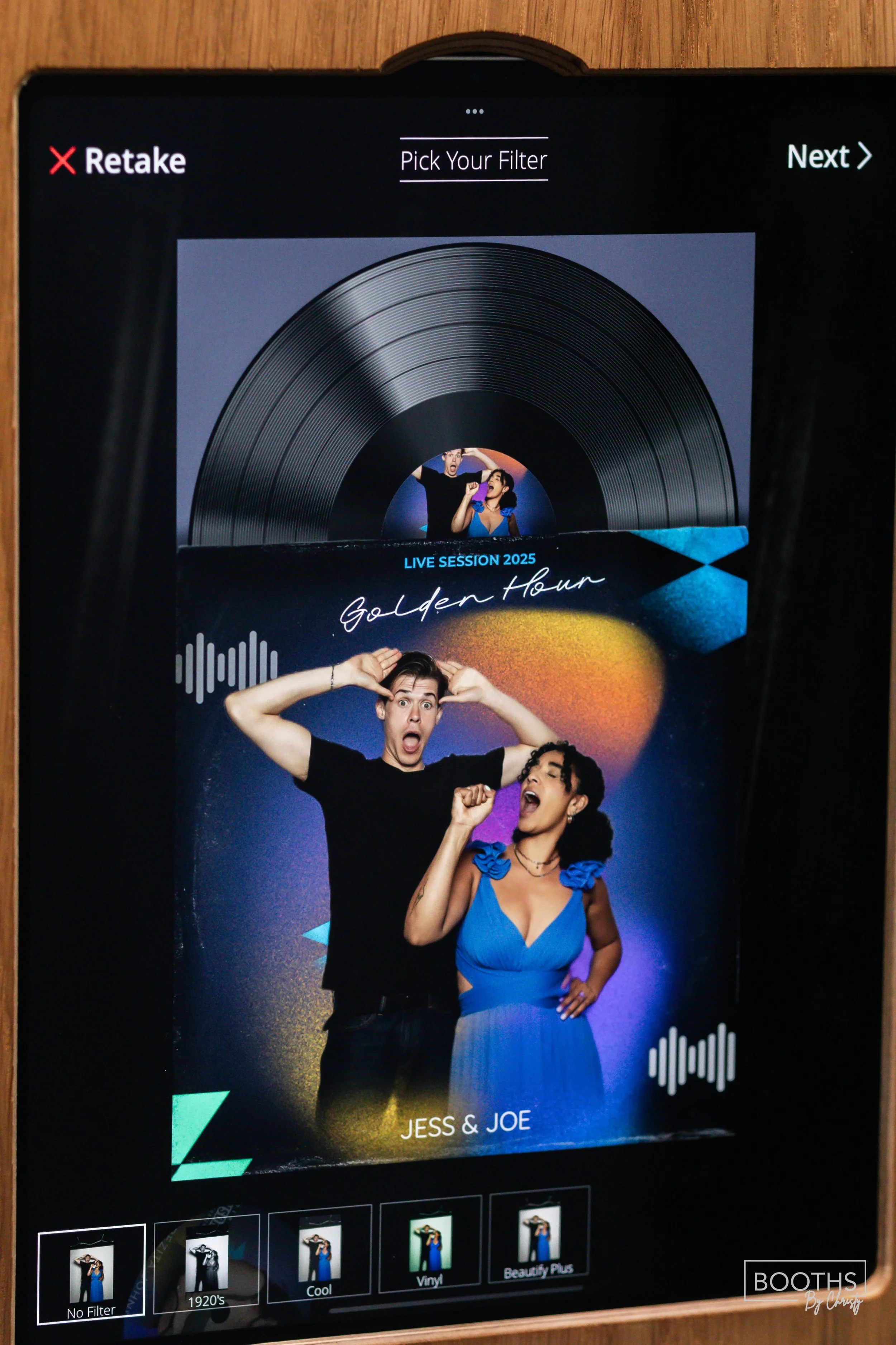 Photo of a digital photo booth screen showing a picture of two people, a man and a woman, with surprised and excited expressions. The background has colorful, abstract lighting effects, and text reads 'LIVE SESSION 2025 Golden Hour Jess & Joe'.