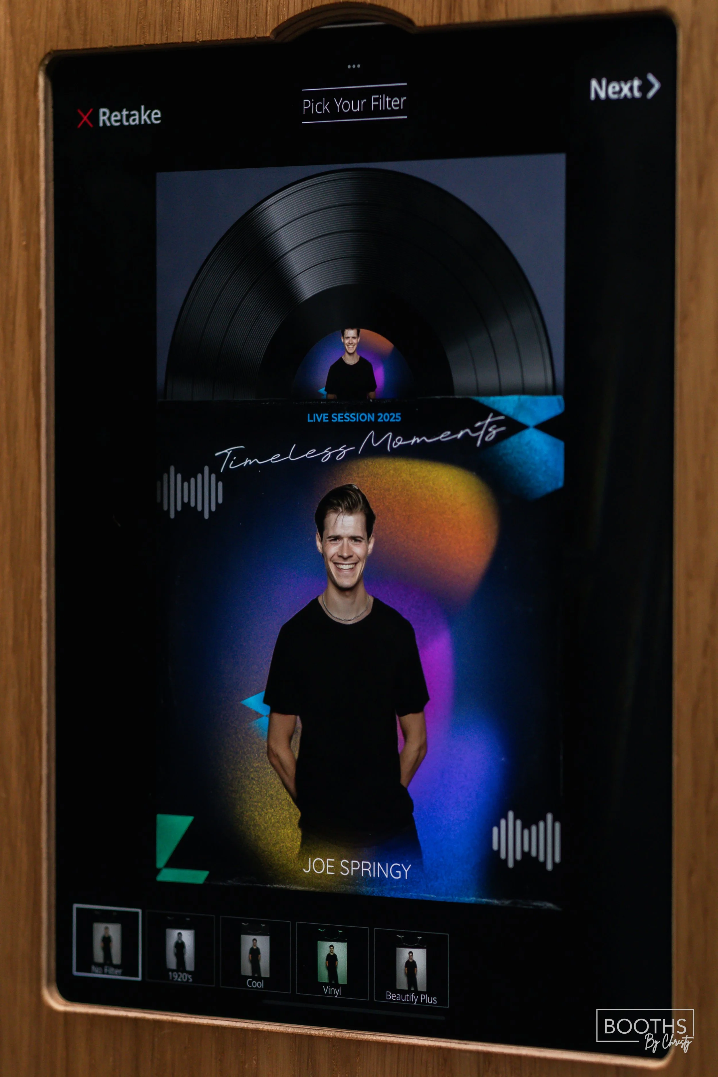 Digital screen showing a photo booth setup with a man smiling, labeled 'Joe Springy,' and various filter options at the bottom.