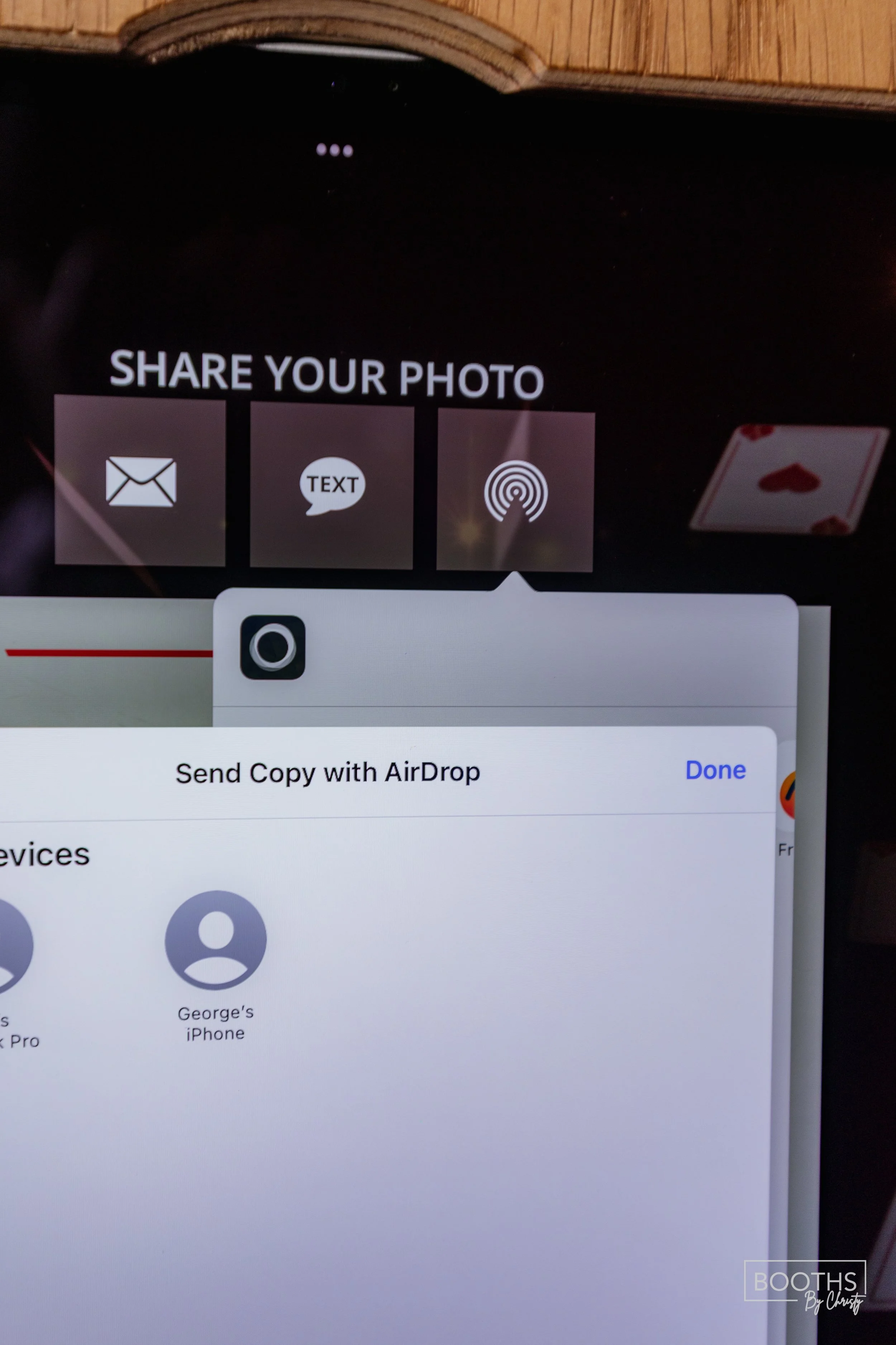 iPhone screen showing options to share a photo via email, text, or AirDrop, with a partial view of a deck of playing cards in the background.