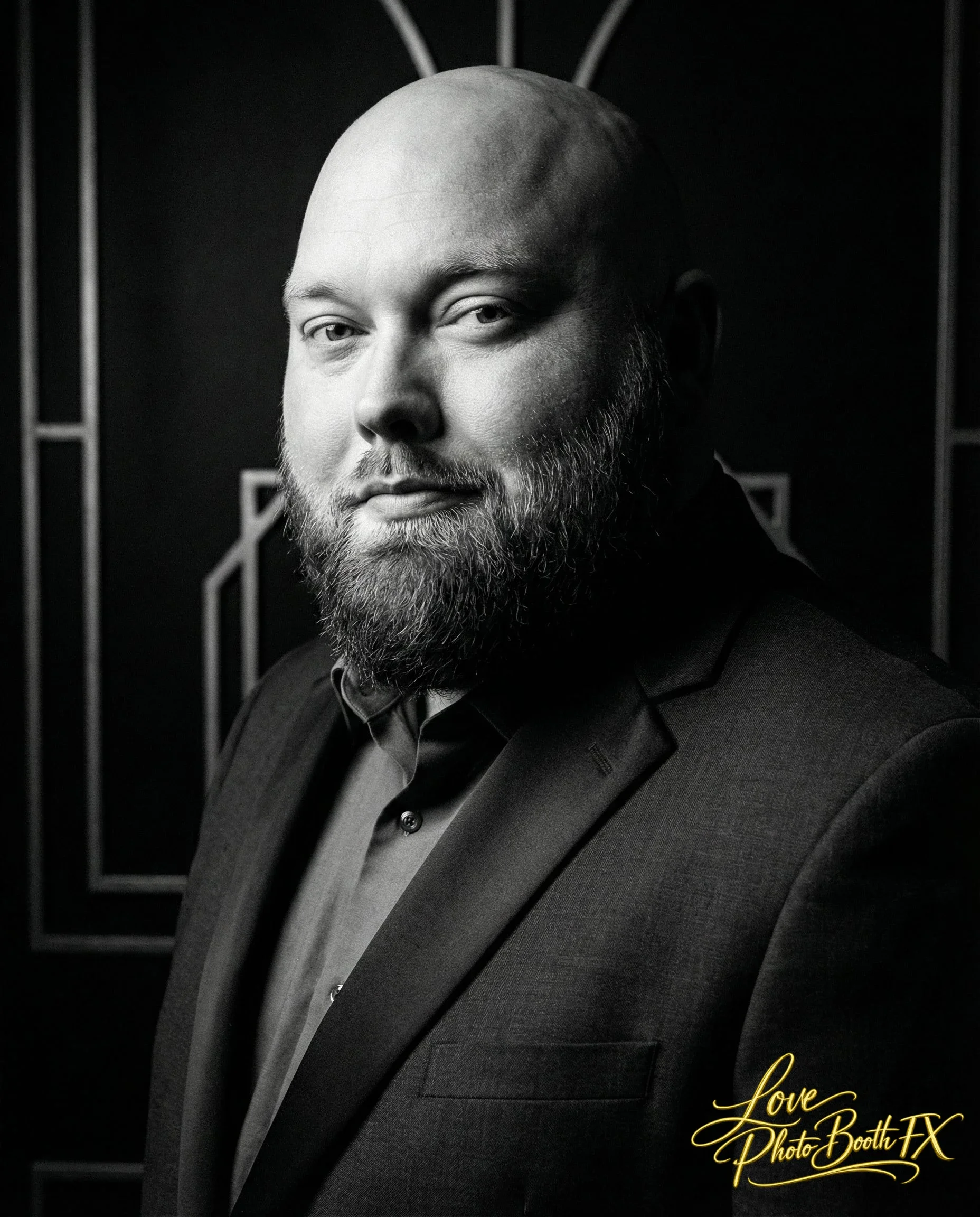 Black and white portrait of a man with a beard, wearing a suit, looking into the camera with a serious expression.