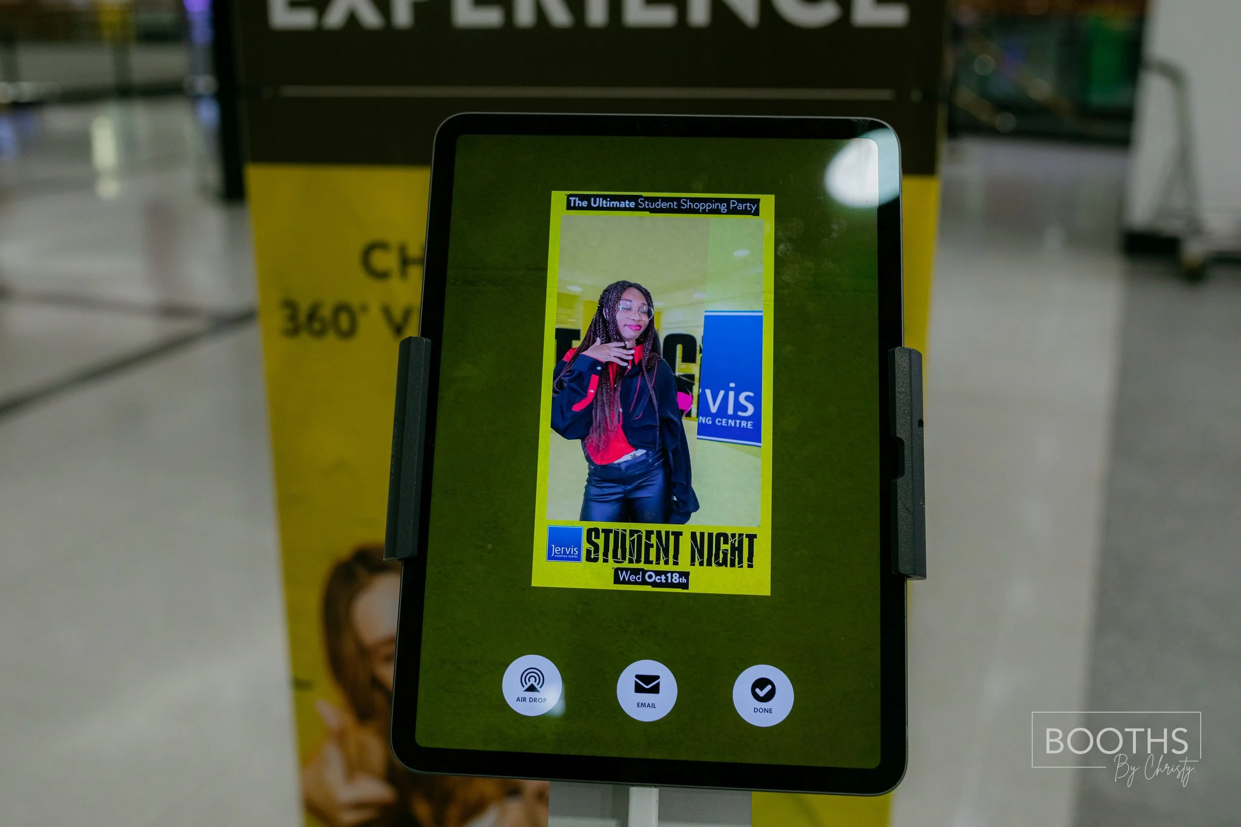 Digital poster on a tablet screen advertising a student night event at Tervis, featuring a woman with braided hair and glasses, wearing a black jacket with red accents, standing in front of a white and blue sign. The background is yellow with black t