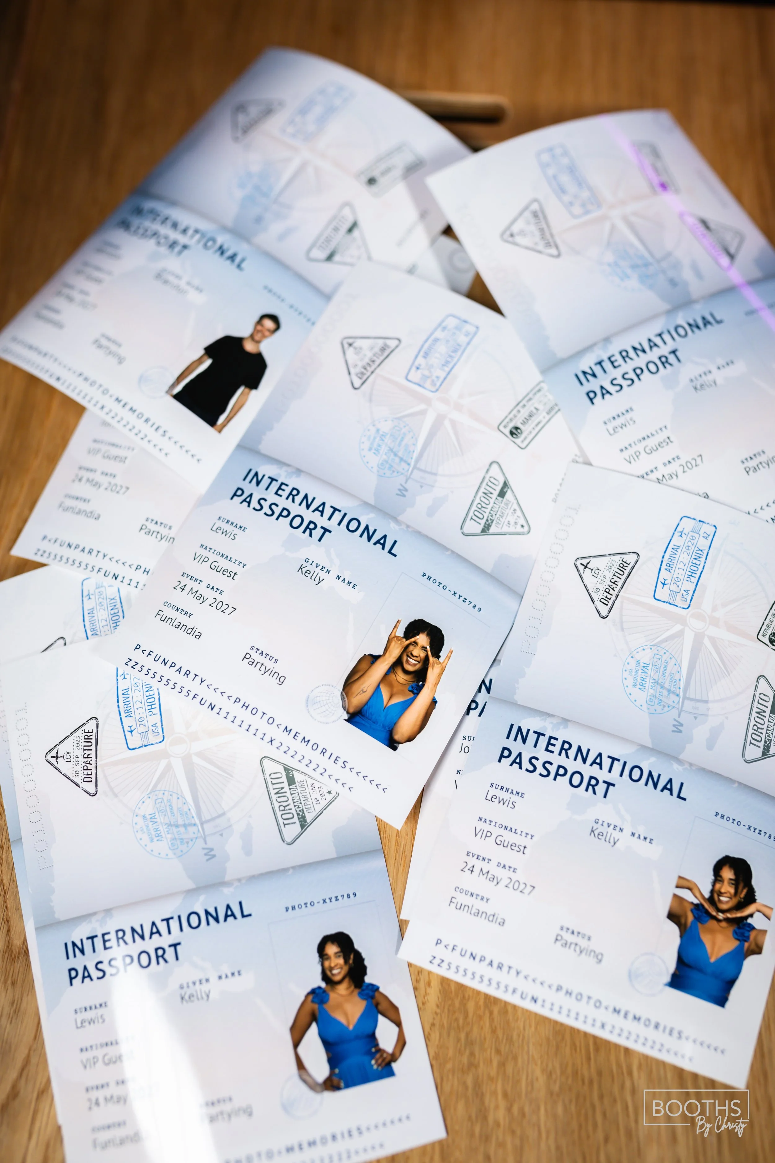 Multiple printed international passports featuring a woman with curly hair and a woman with straight hair, smiling and posing in a blue dress, on a wooden surface.