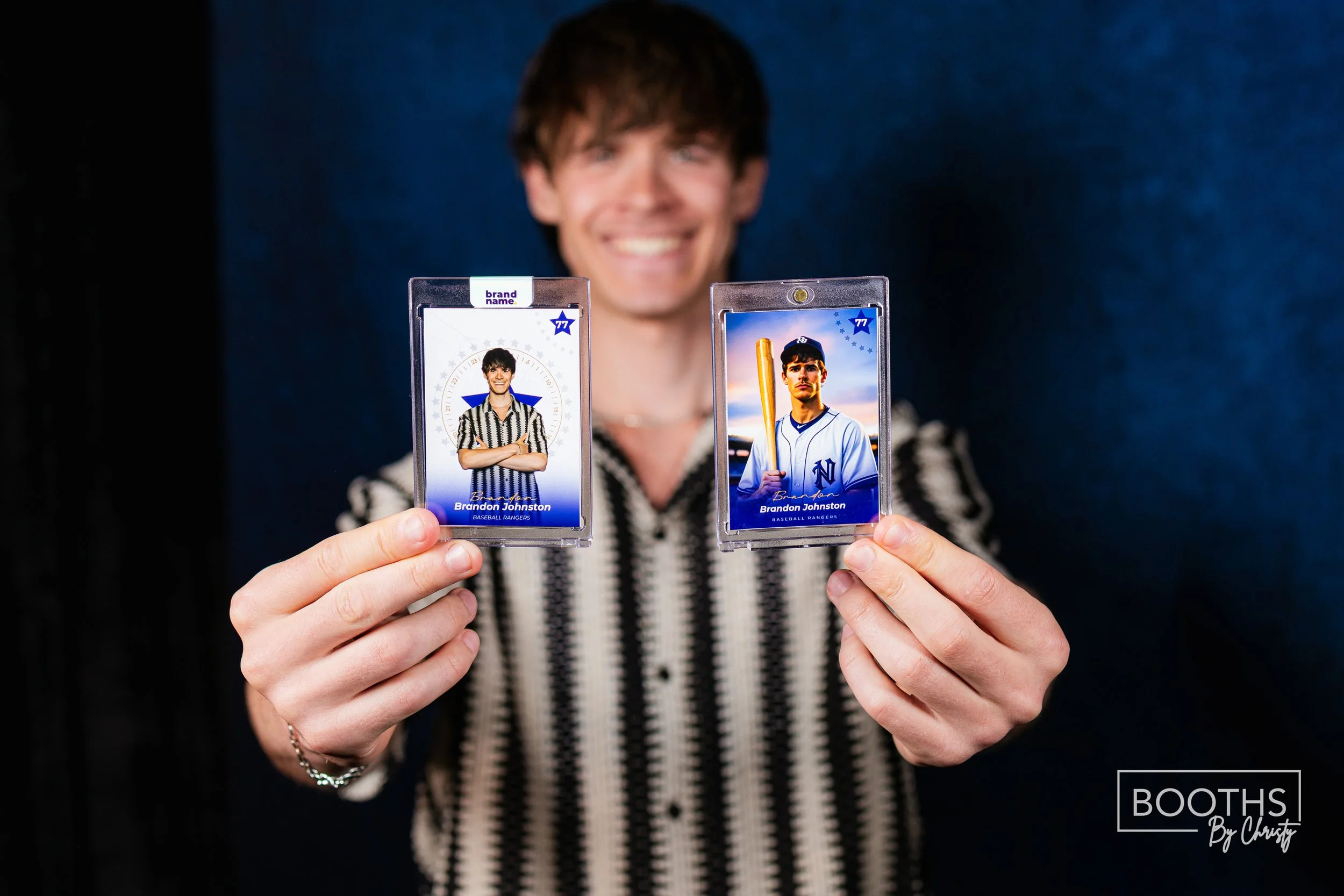 Person holding two digital sports cards, one of a baseball umpire and one of a baseball player with a bat, in front of a dark background.