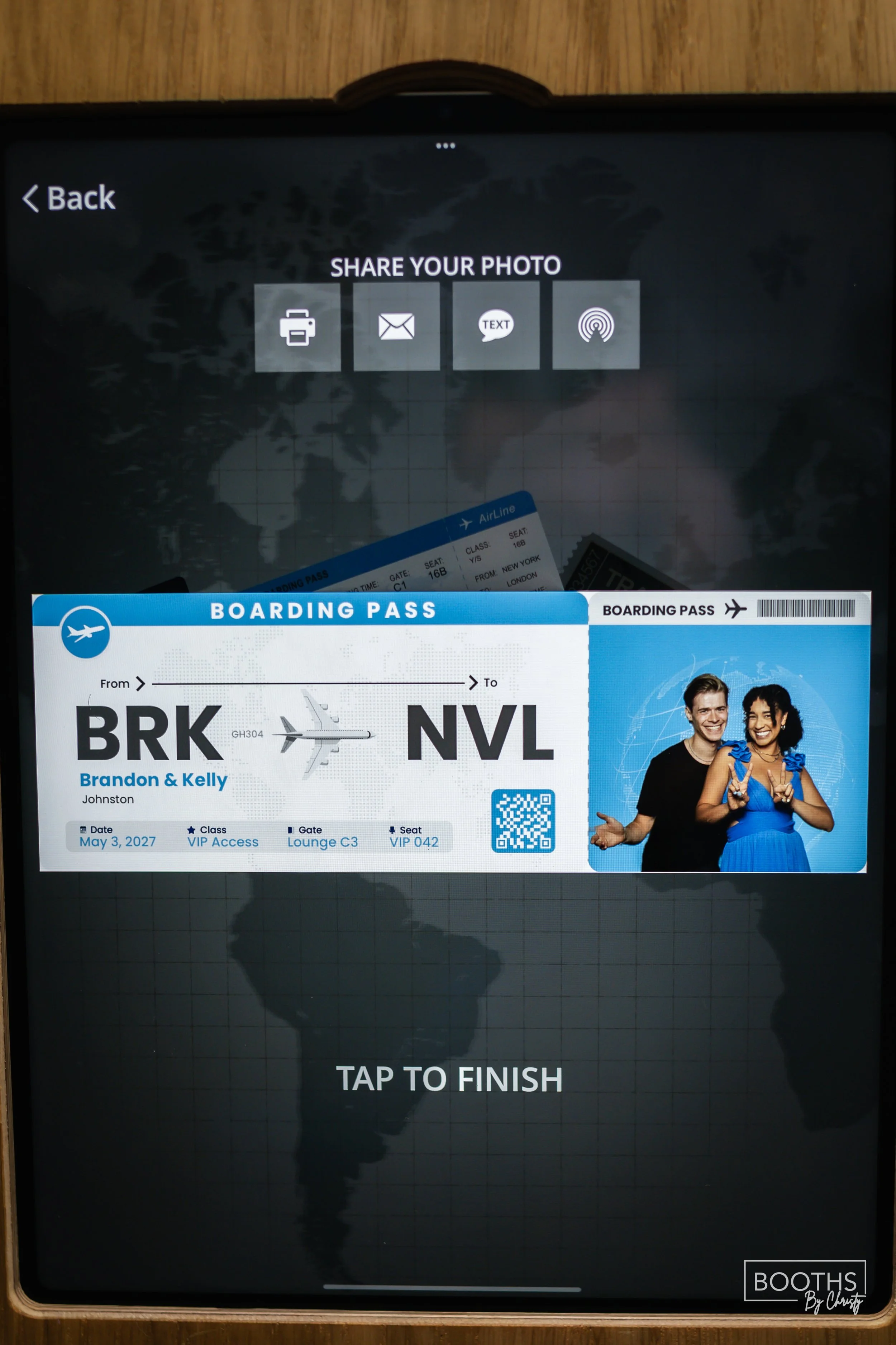 A digital device screen displaying a boarding pass for Flight GH304 from Brussels to New York City, showing the date May 3, 2027, with the names Brandon & Kelly. The screen also has options to share the photo via print, email, text, or airplay.