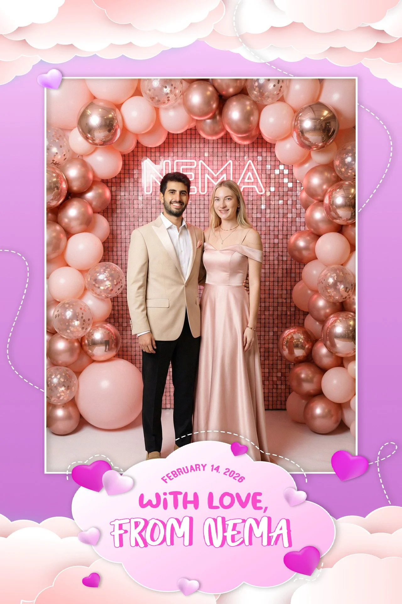 A man and woman in formal attire smiling and posing together at a Valentine's Day event, standing in front of a pink balloon arch and a neon sign that says "NEMA." The woman is wearing a light pink satin off-shoulder gown, and the man is in a beige b