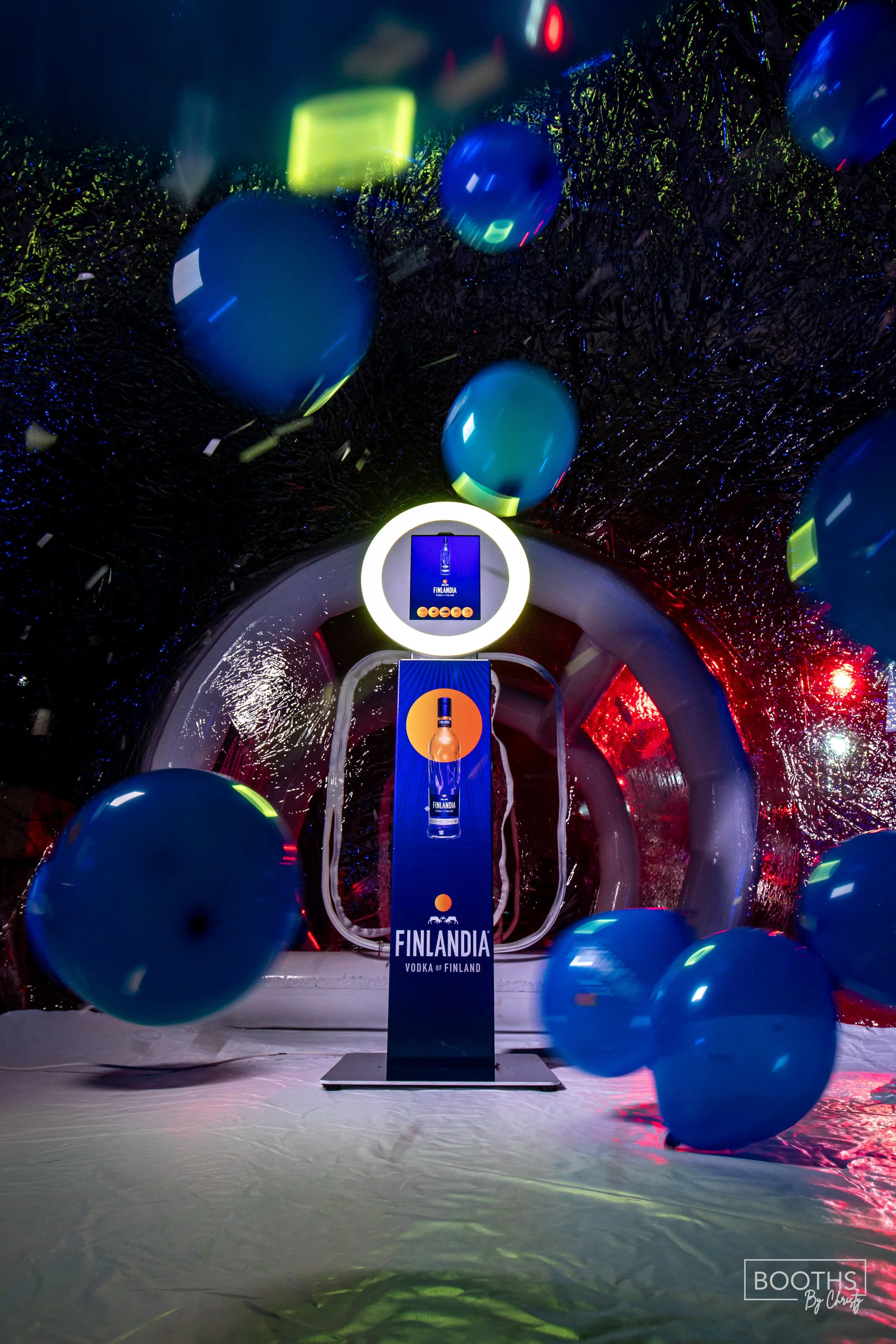 A Finlandia vodka display with blue balloons floating around in a reflective, possibly glass or plastic, archway at a promotional event.