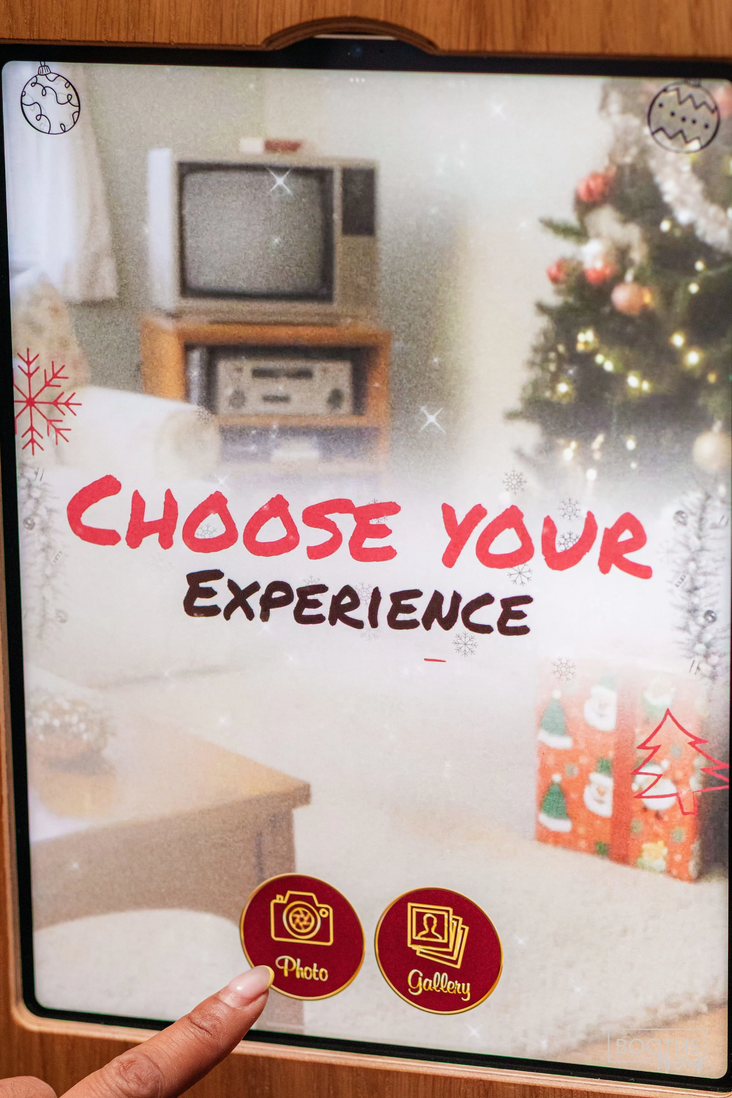 Screen with the text 'Choose Your Experience' and options for 'Photo' and 'Gallery,' set against a blurred background of a living room decorated for Christmas, including a Christmas tree with ornaments and wrapped presents.