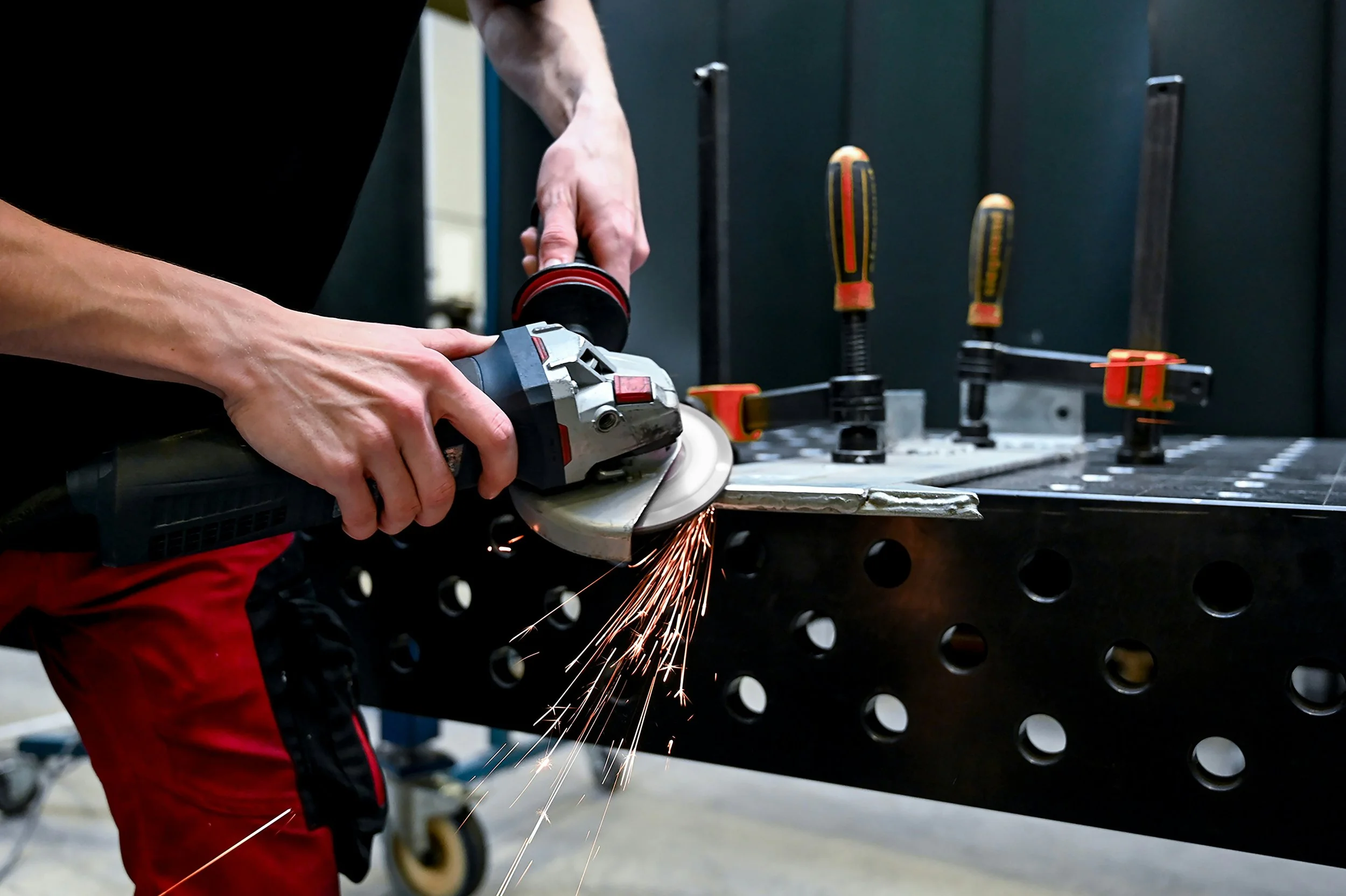 Man using angle grinder on metal welds