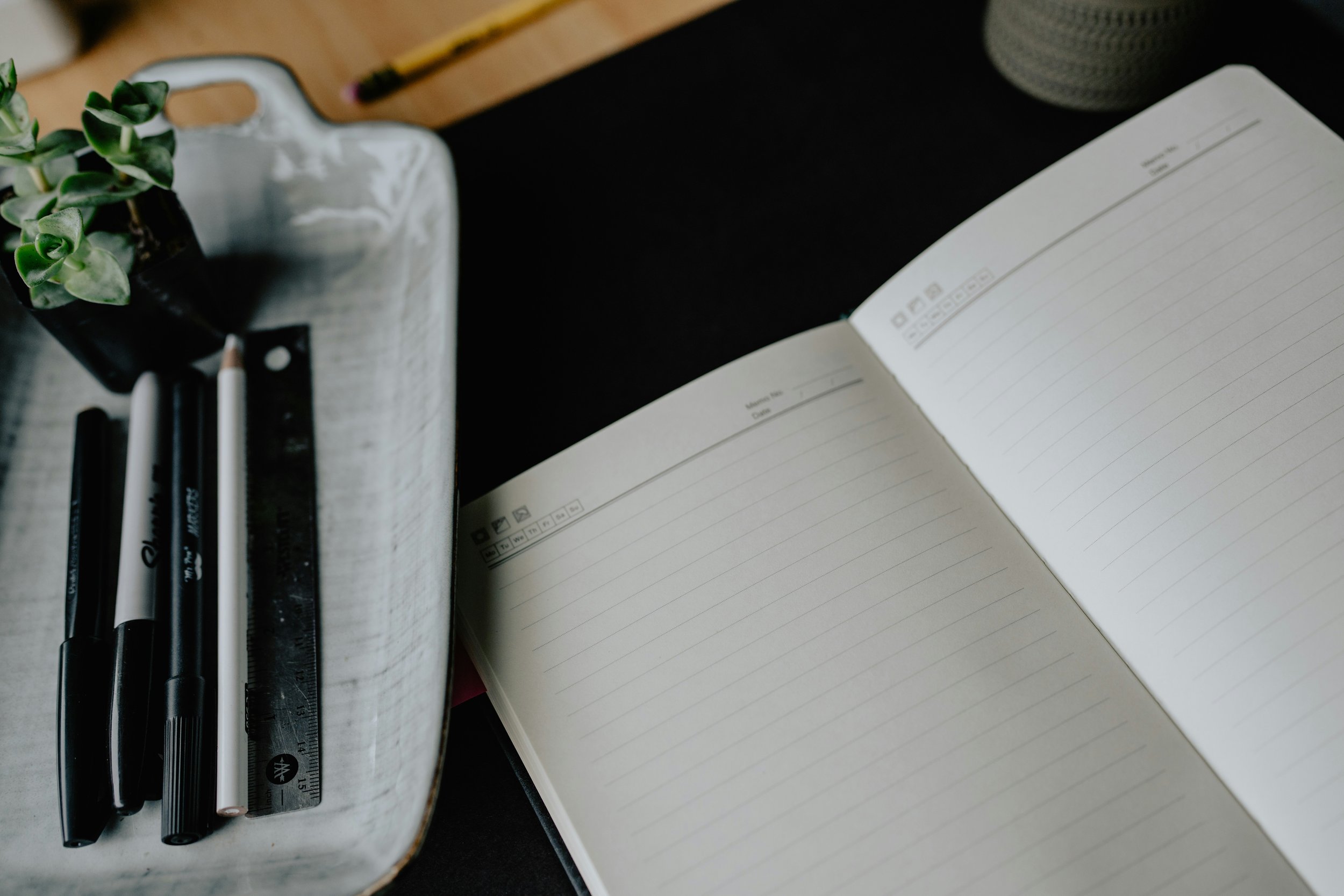 An open blank notebook and pens on a gray desk