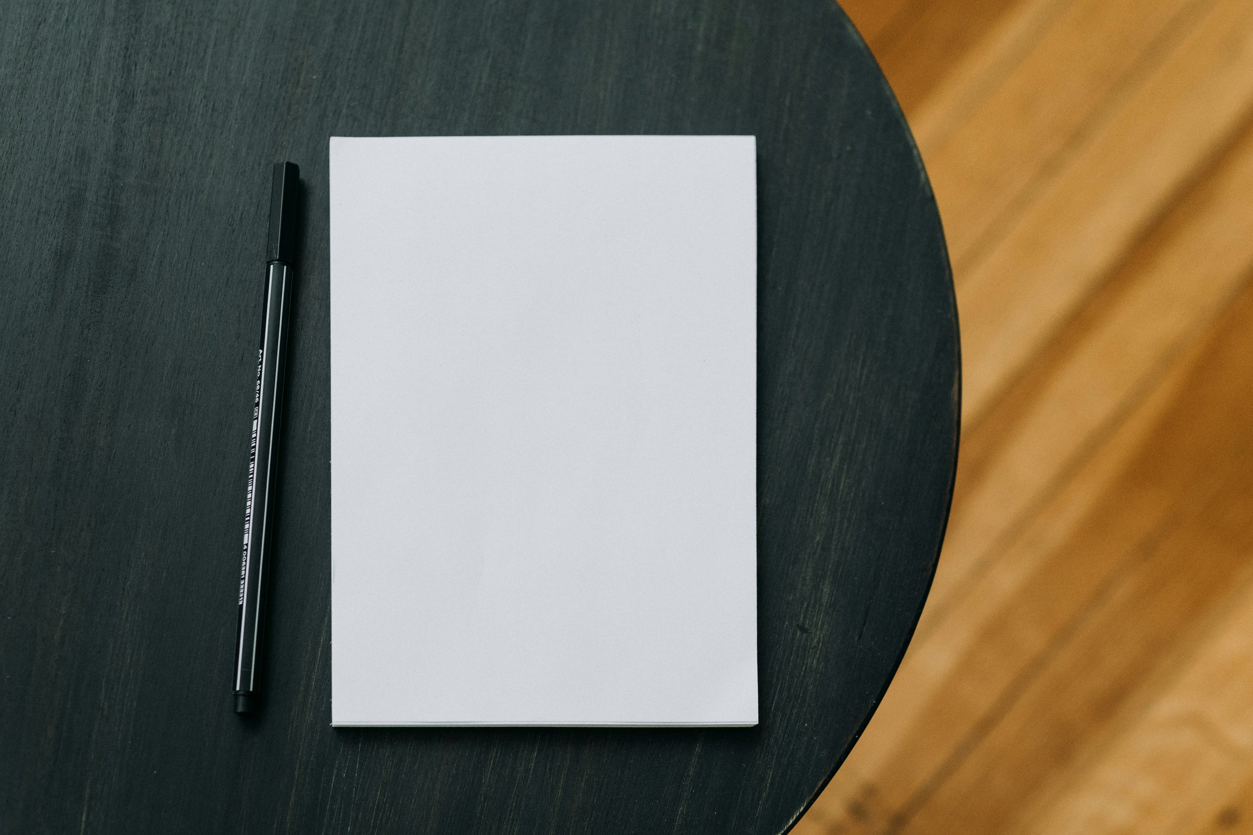 Notepad and a pen on a wooden table