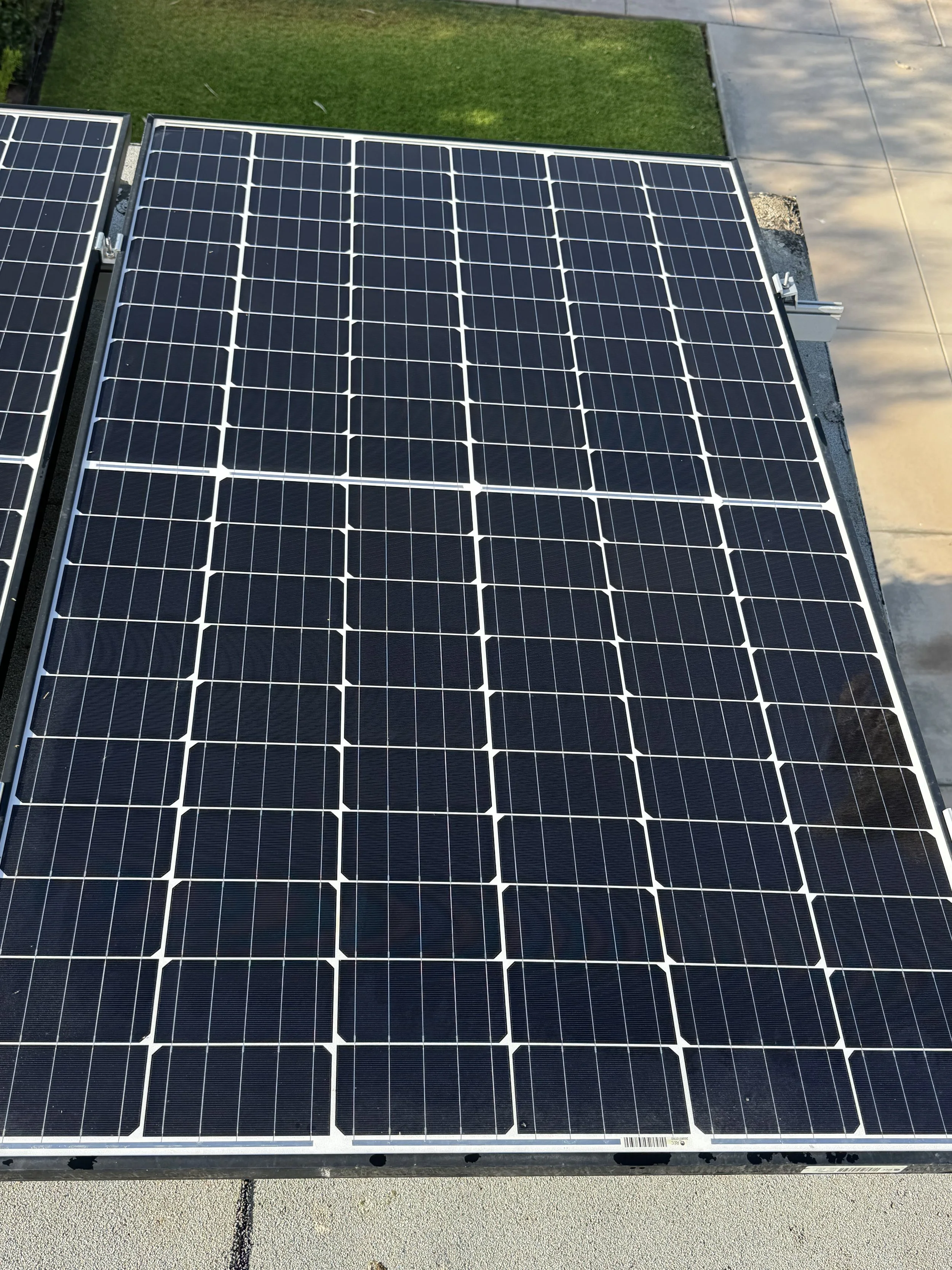 Solar panels installed on a building's roof with a patch of green grass visible nearby.