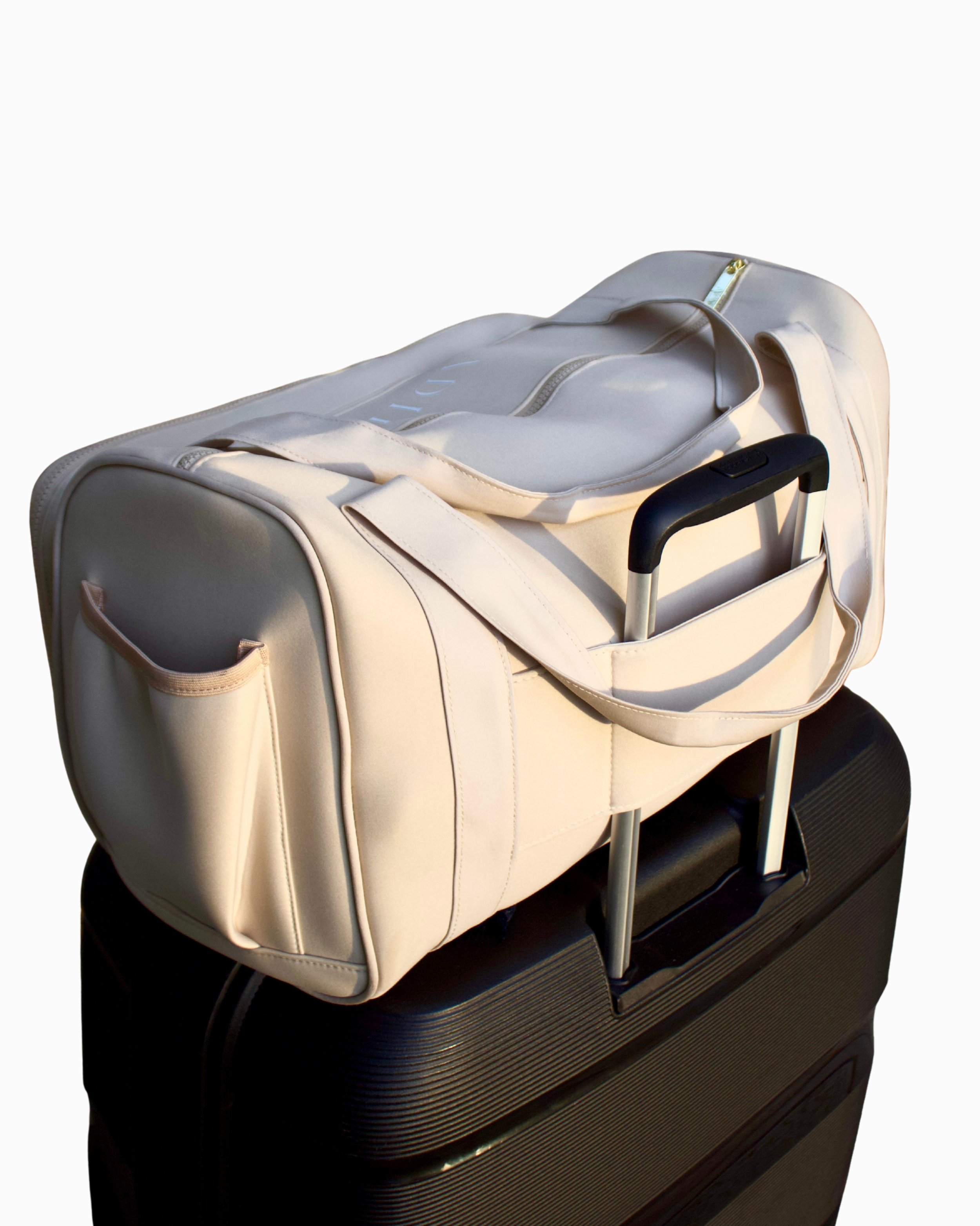 Back view of the Adieu Core Duffle secured on a suitcase using the luggage slip – a carry-on friendly women’s weekender bag.