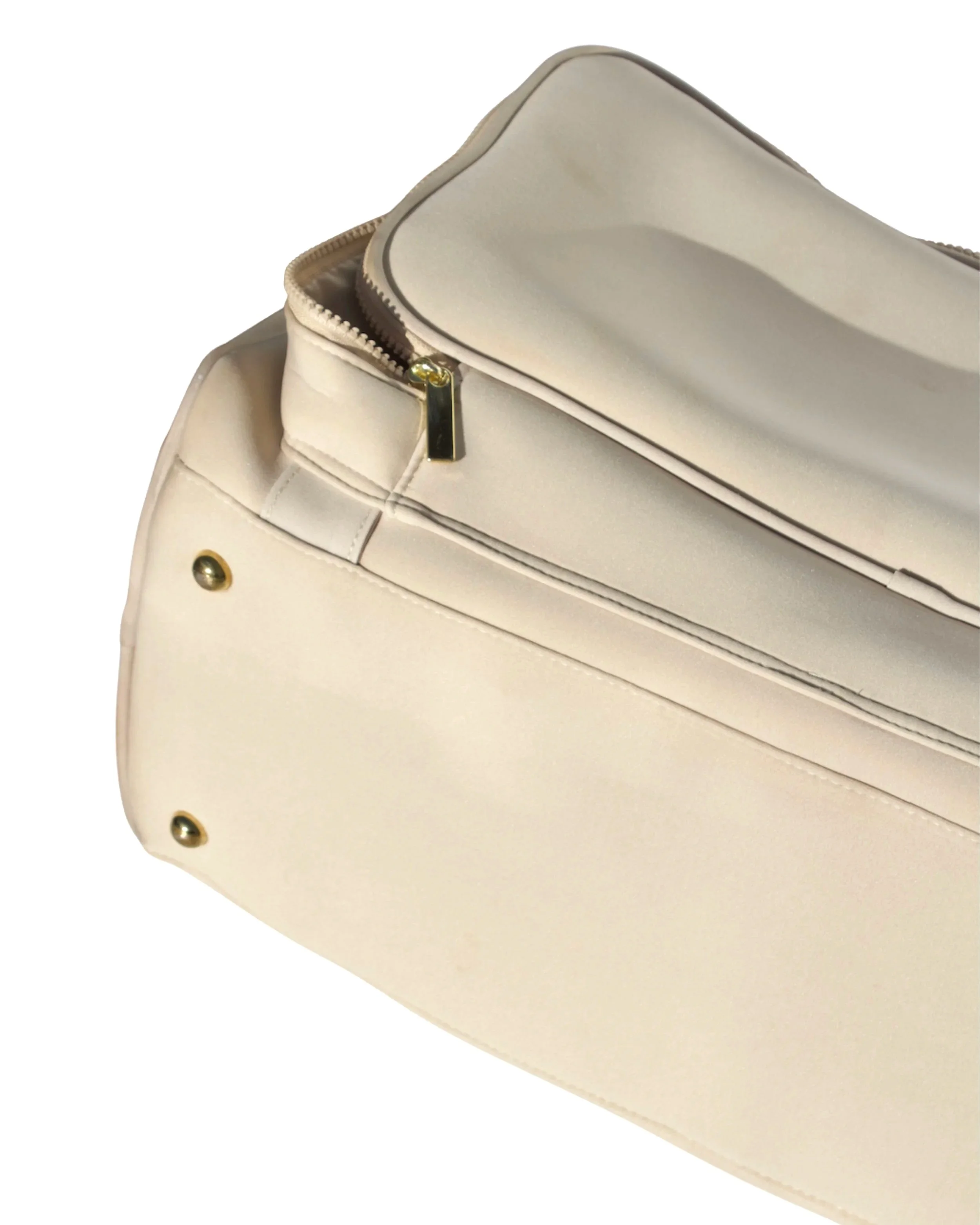Base of the beige Adieu Core Duffle showing protective gold studs designed to keep the bag clean and elevated.