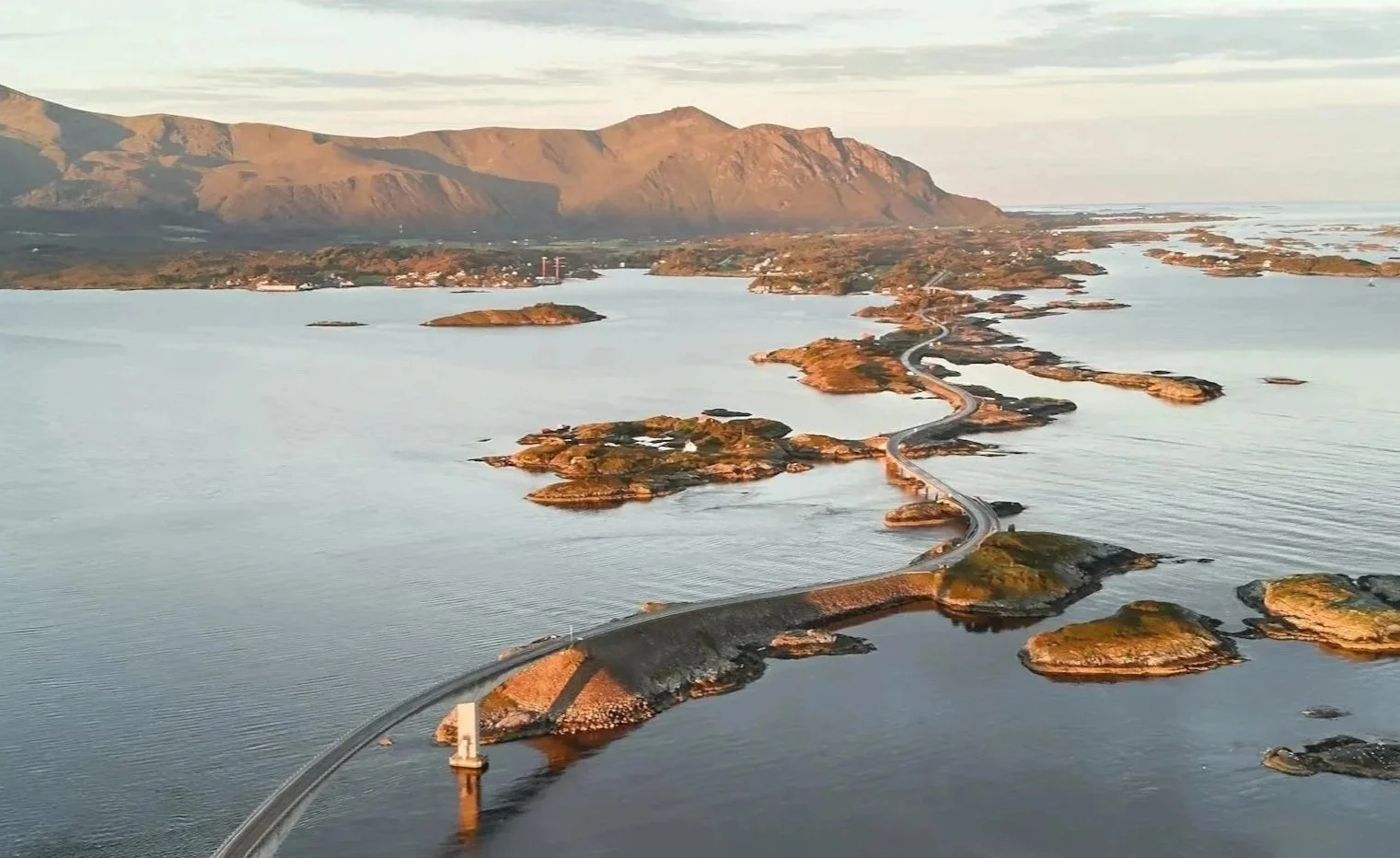 Fjell og små øyer omgitt av sjø, med en veikorridor som går gjennom øyene, og fjell i bakgrunnen.