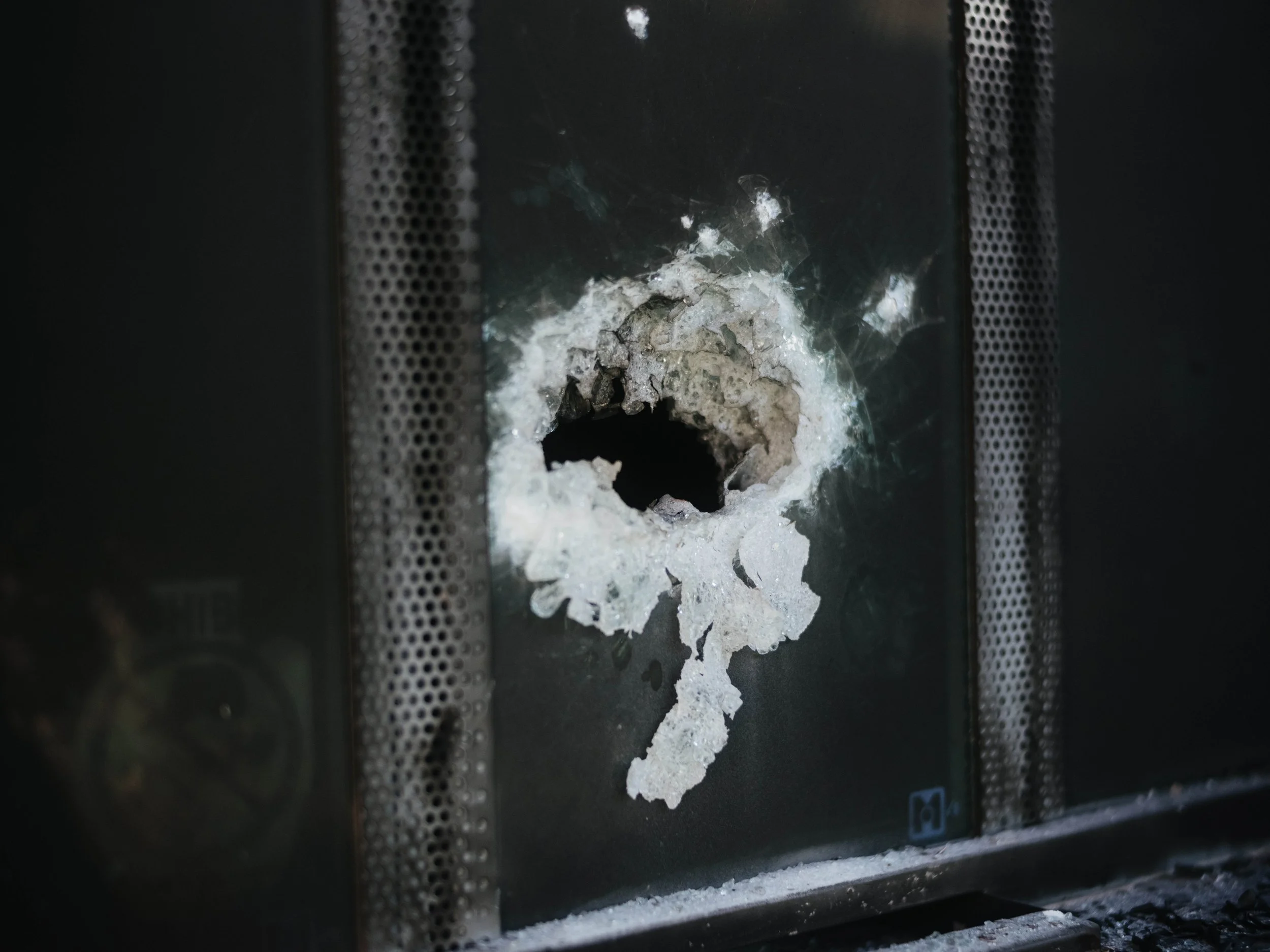 A large bullet hole is visible on a damaged surface inside a bank in Aguililla, Michoacán.