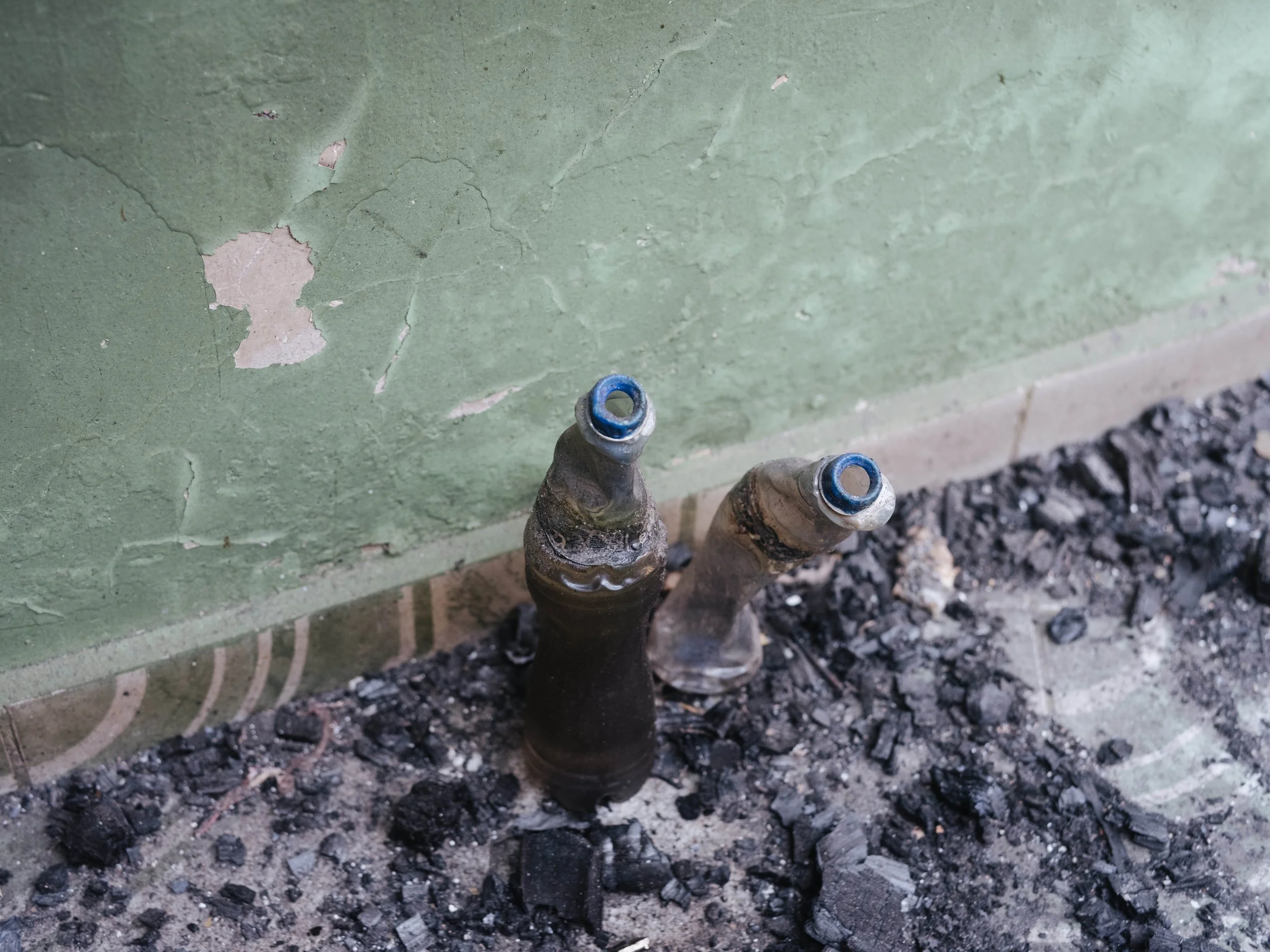 Burned glass bottles remain among debris inside a damaged space in Aguililla, Michoacán.