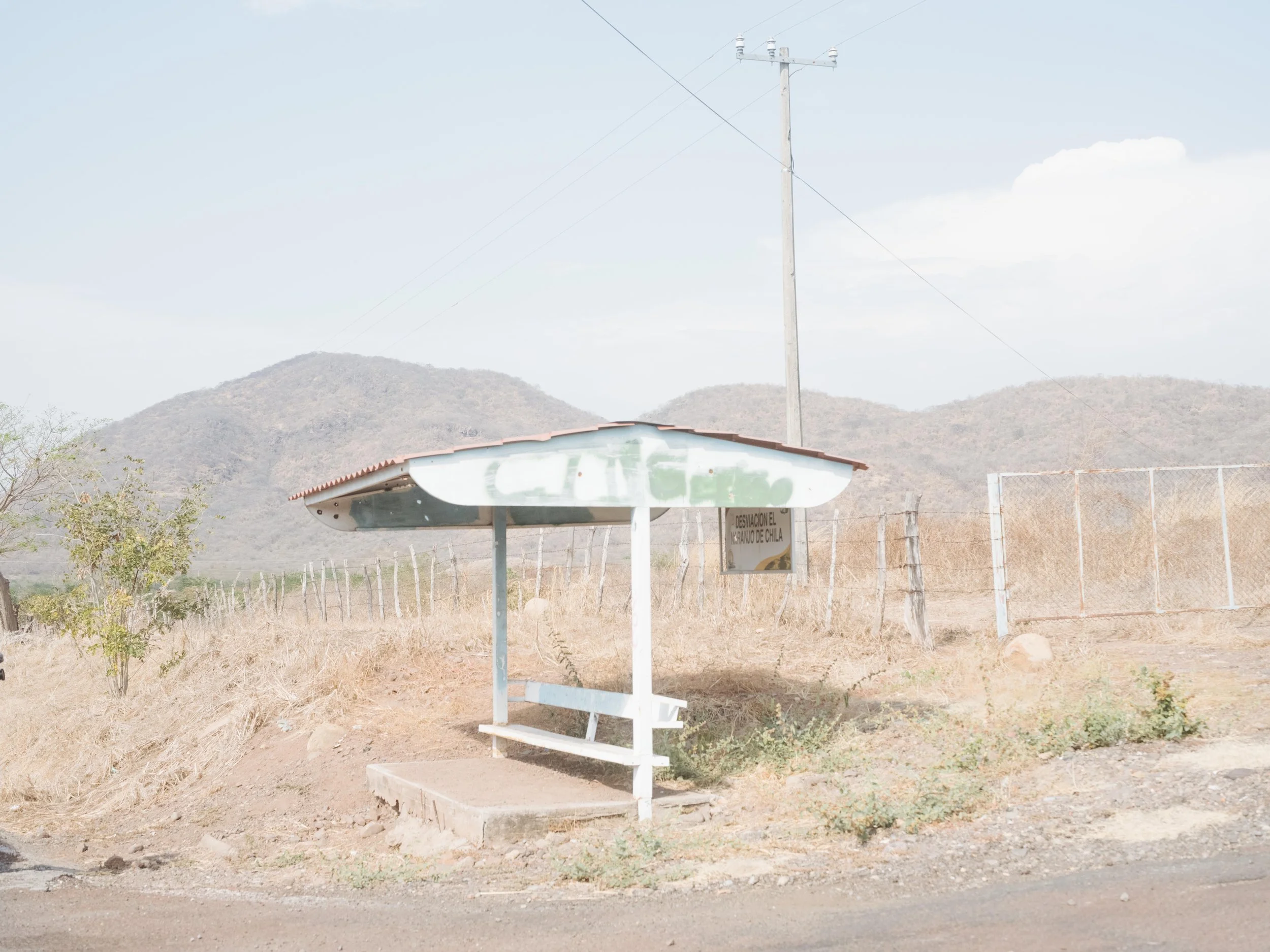 A bus stop near Naranjo de Chila, in the municipality of Aguililla, Michoacán, bears the faded initials “CJNG,” a reference to the Jalisco New Generation Cartel, in a region shaped by years of violence and territorial control.