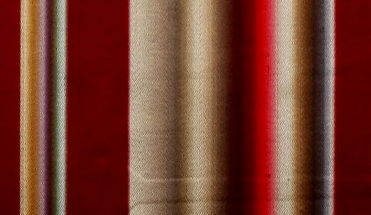 Close-up of a fabric with vertical red, beige, and white stripes.