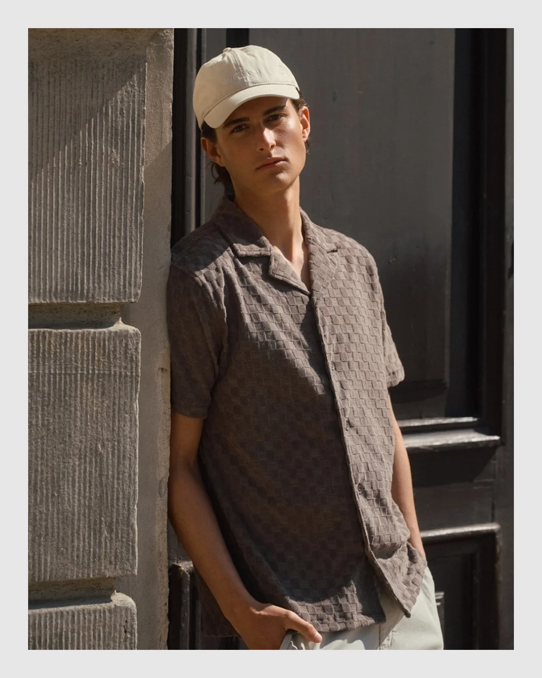 Male model wearing a textured brown short-sleeve shirt and cap by Brothers
