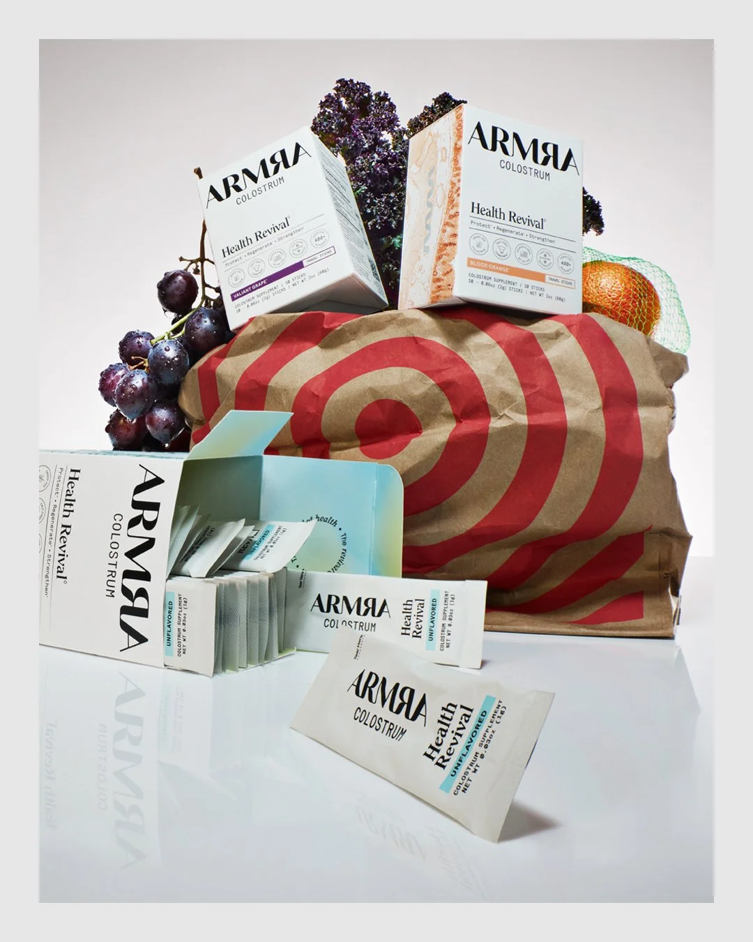 ARMRA colostrum products arranged with fruit and a shopping bag