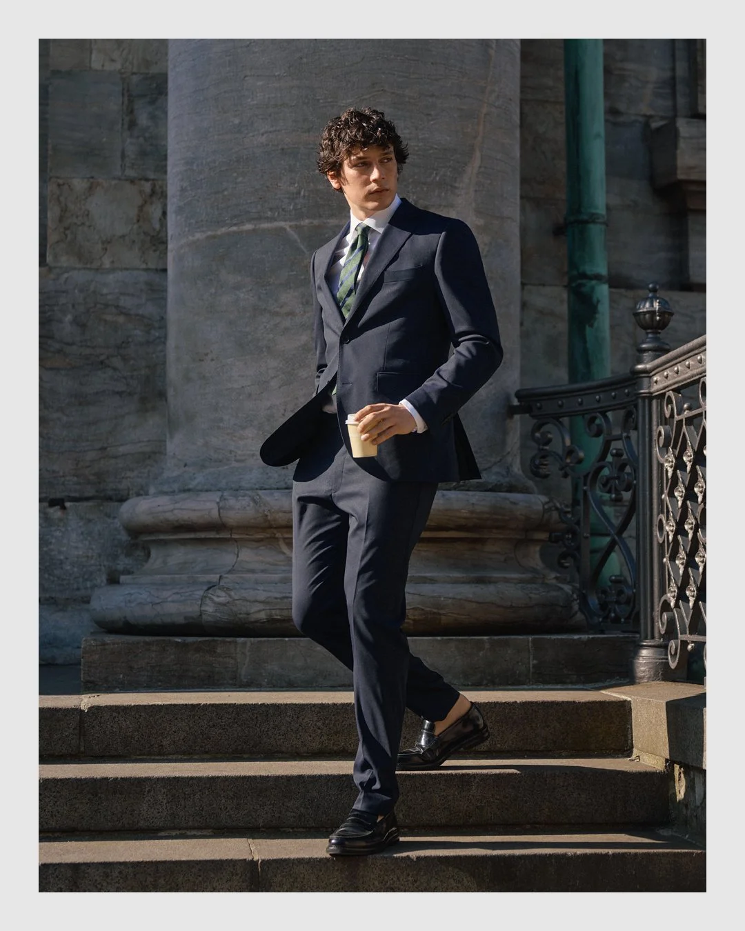 Brothers tailoring with male model wearing a navy suit and striped green tie