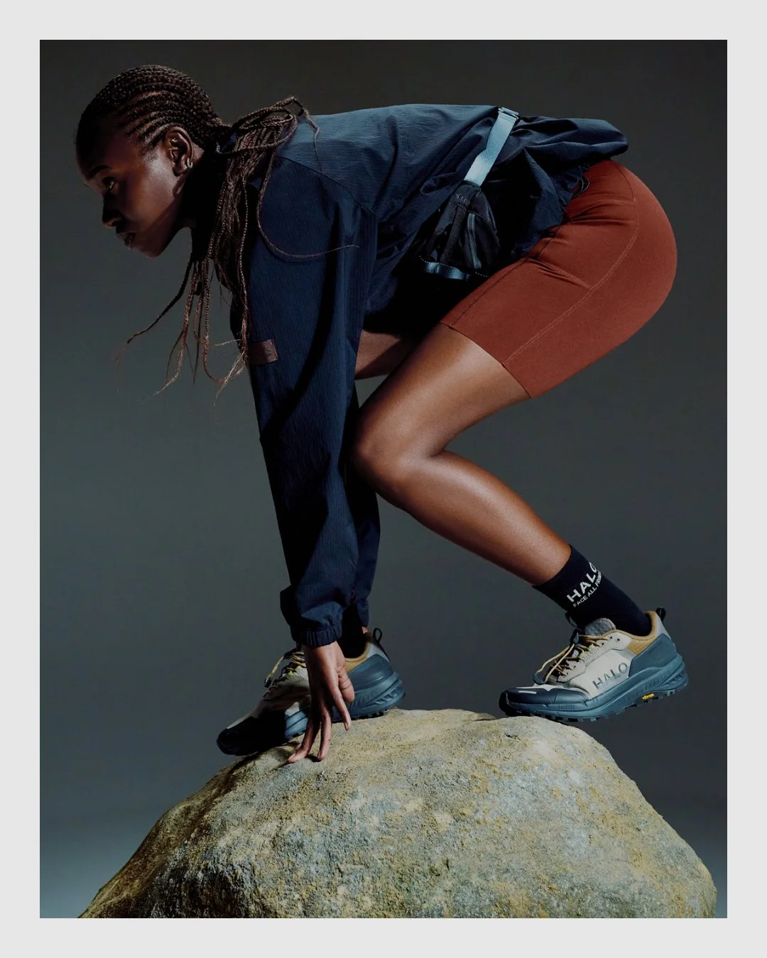 HALO performance campaign image of female model posed on rock in technical clothing