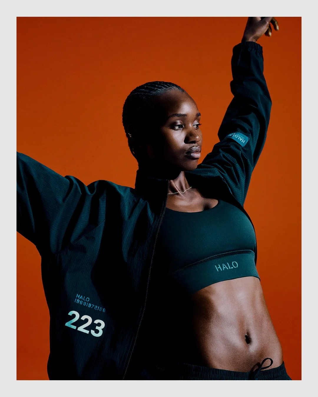 HALO campaign portrait in dark performance clothing against saturated orange background