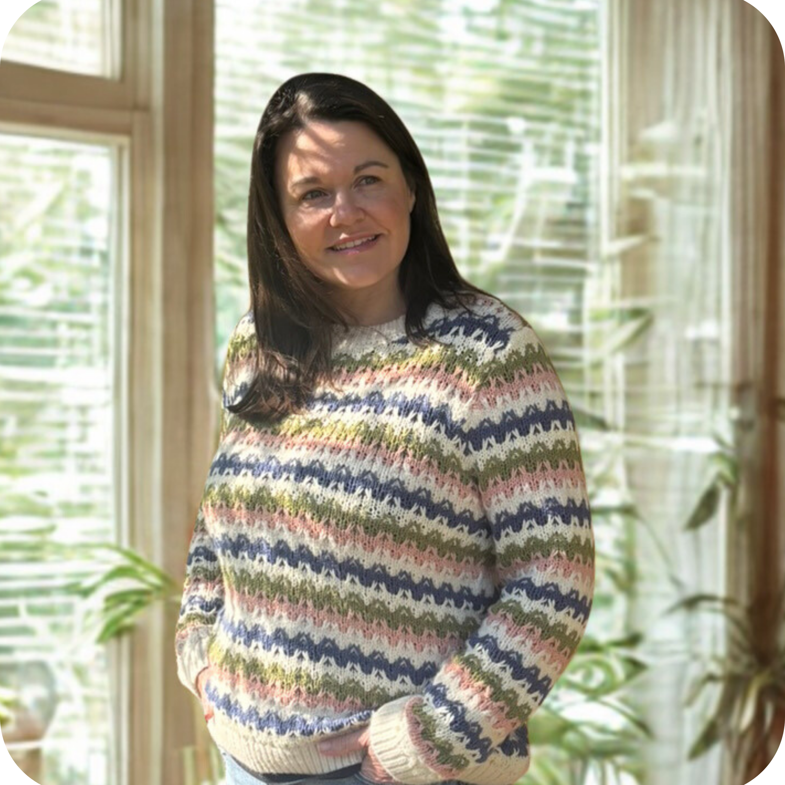 A white desk with a yellow mug, a laptop, a closed notebook, and a woven basket with white flowers sitting on top, against a yellow wall background.