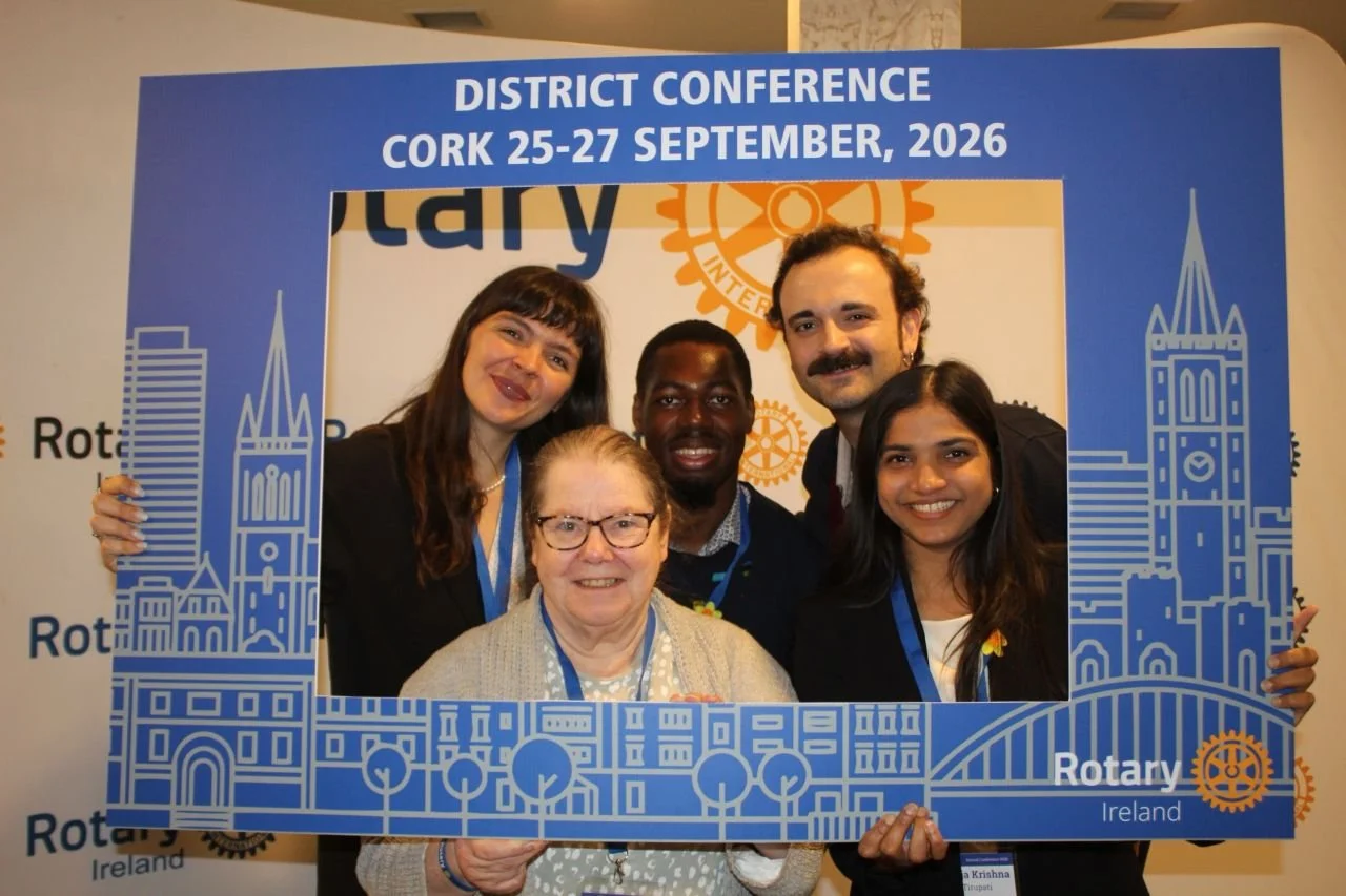 Five people with a Rotary Ireland photo board that says district conference Cork 25-27 September 2026
