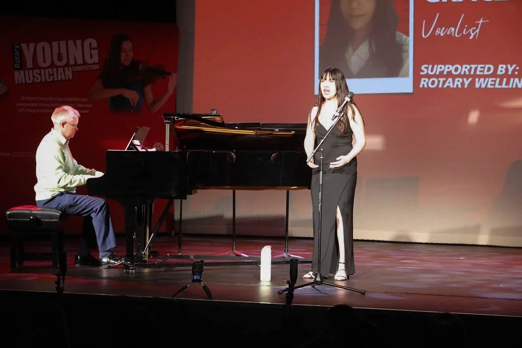 A woman signing next to a man playing the piano