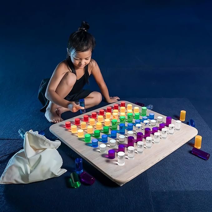 A young girl playing a colorful board game with large, multicolored pieces on a wooden table.