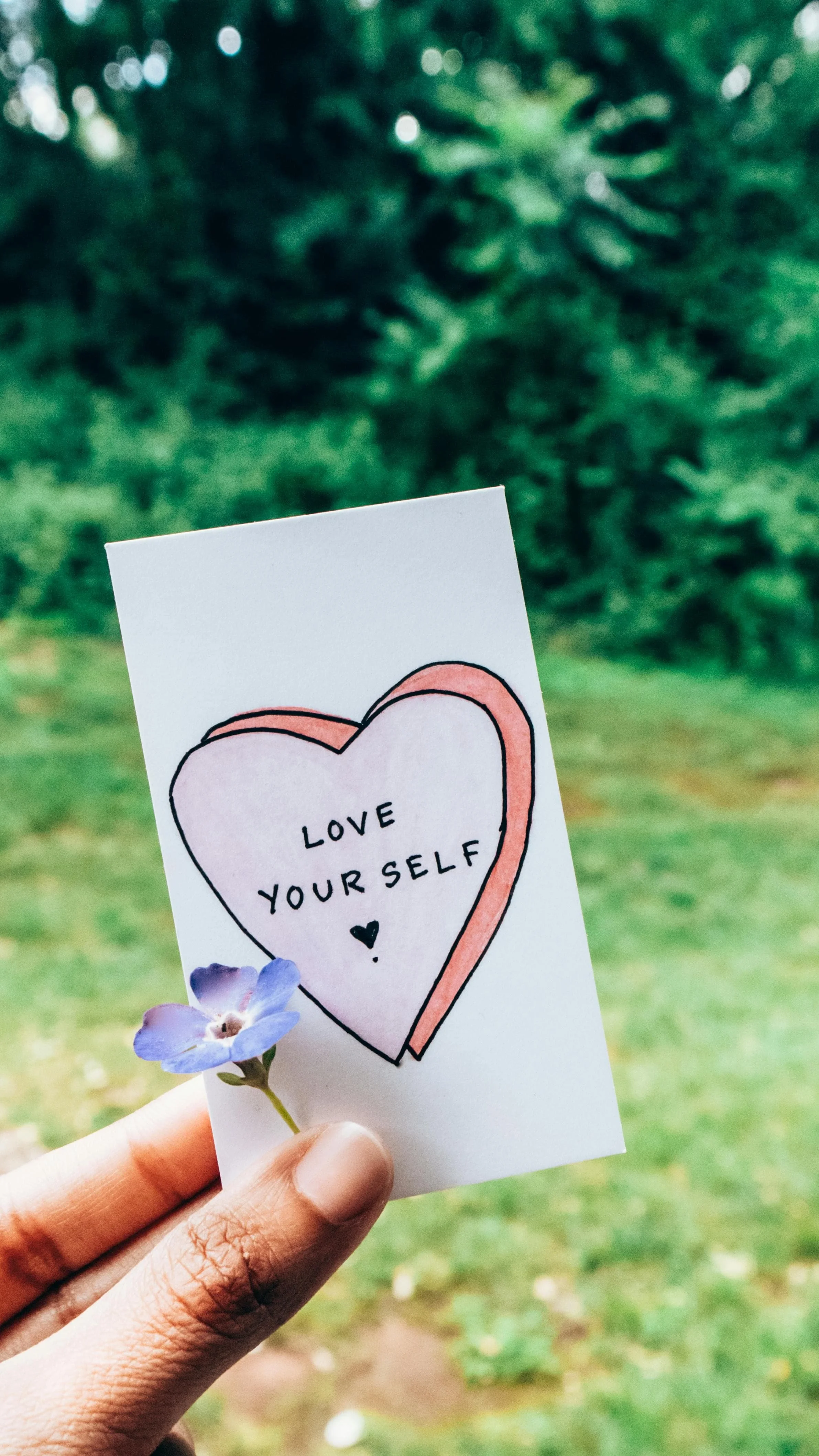 In York, PA, some holds up a flower and a note that says "Love Yourself" after a virtual therapy session with Catsam Wellness.
